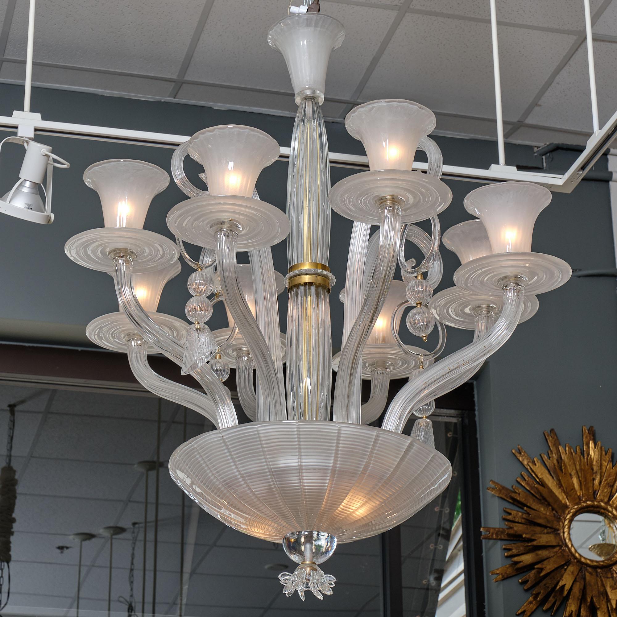 Italian chandelier from the island of Murano. This exquisite chandelier has eight branches and four curled up stems with ridged glass components hanging off of each stem. Brass details can be found in the middle section of the chandelier. This piece