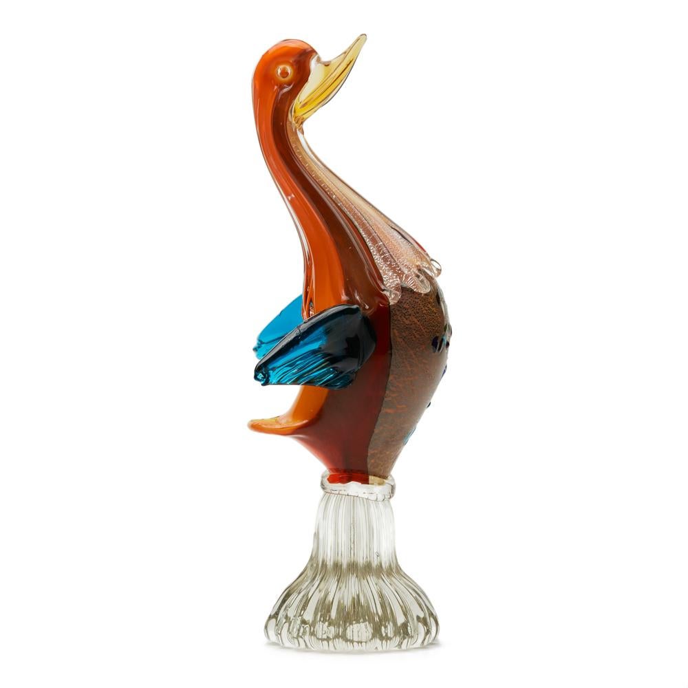 A fine and stylish mid-century unusual Italian, Murano glass bird in cased colored glass . The bird stands raised on a tall clear glass ribbed round base with orange and mottled brown cased glass body and neck, the neck with run down clear glass
