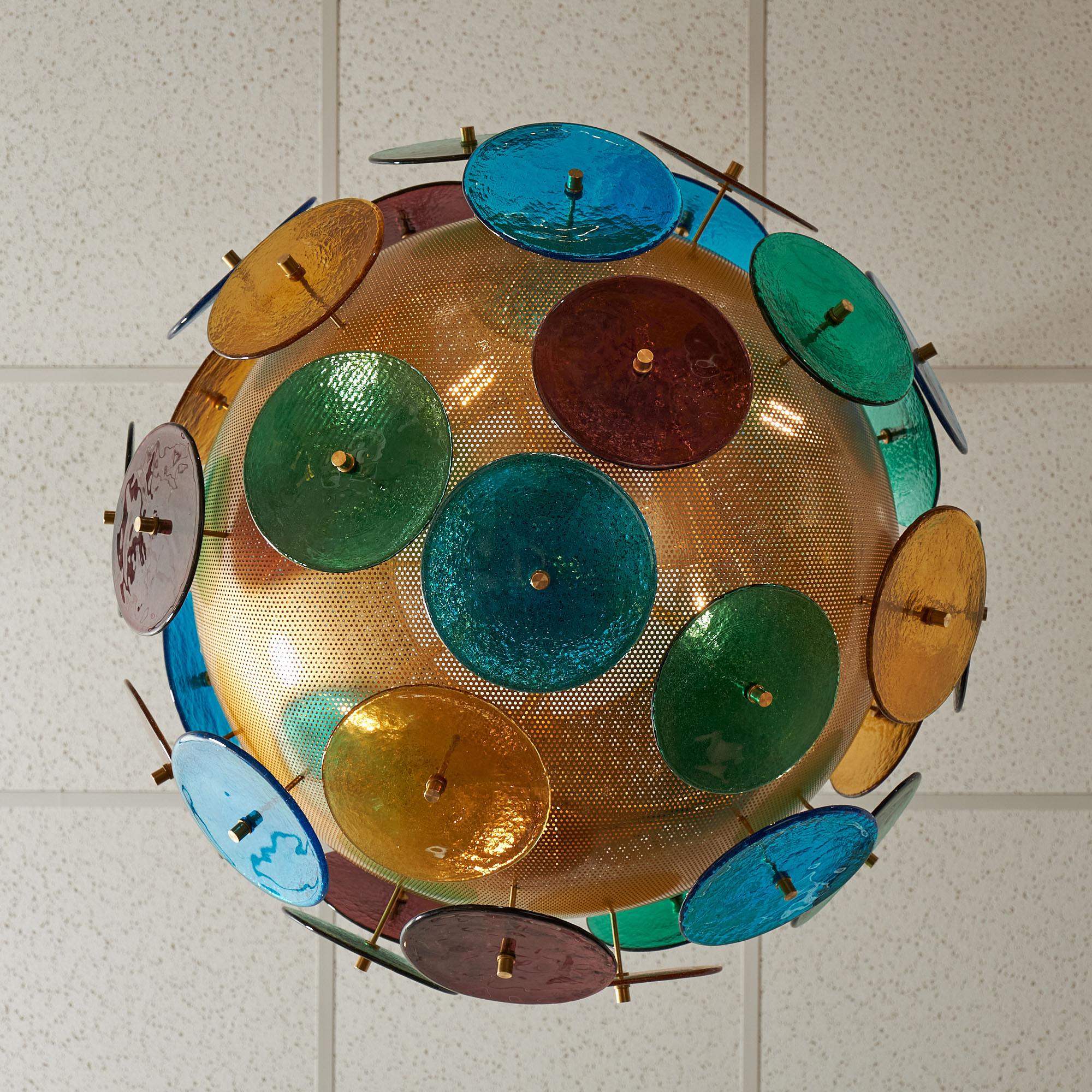 Un lustre Sputnik vintage de Murano, en Italie. La lumière brille à travers une sphère perforée en laiton galvanisé. Des disques à pied multicolores en verre de Murano dépassent des sphères. 
