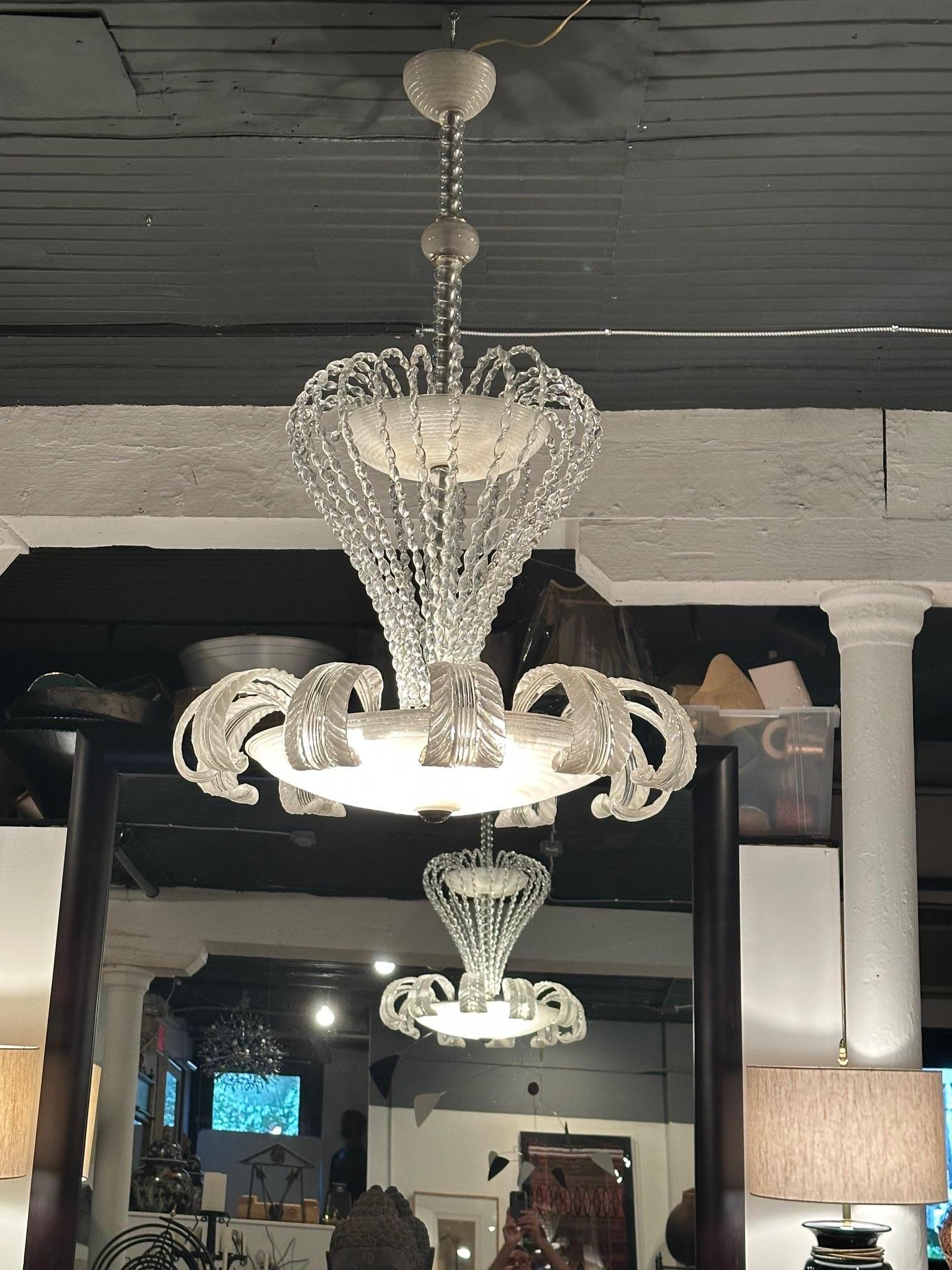 Lampadario di Murano super scenografico che fa pensare a una magica creatura marina galleggiante.  Appena ricablata, a due livelli con foglie in vetro soffiato intorno al cerchio illuminato inferiore.
3 lampadine nella parte inferiore
