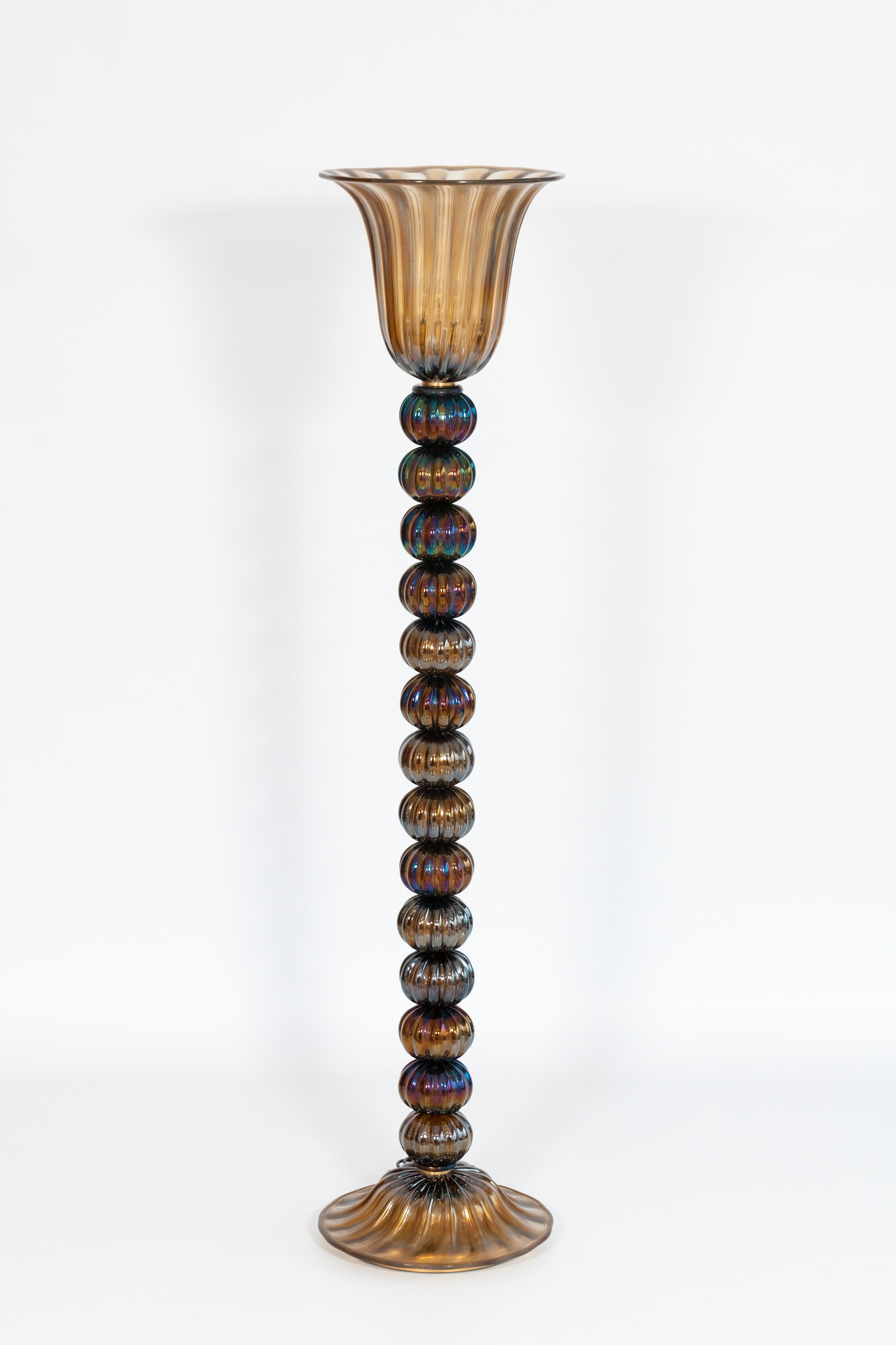 Wir präsentieren eine exquisite und visuell fesselnde Murano-Glas-Stehlampe, die von der renommierten Vintage Murano Gallery in den 1980er Jahren geschaffen wurde. Dieses eindrucksvolle Stück verkörpert die einzigartige Mischung aus Kunstfertigkeit