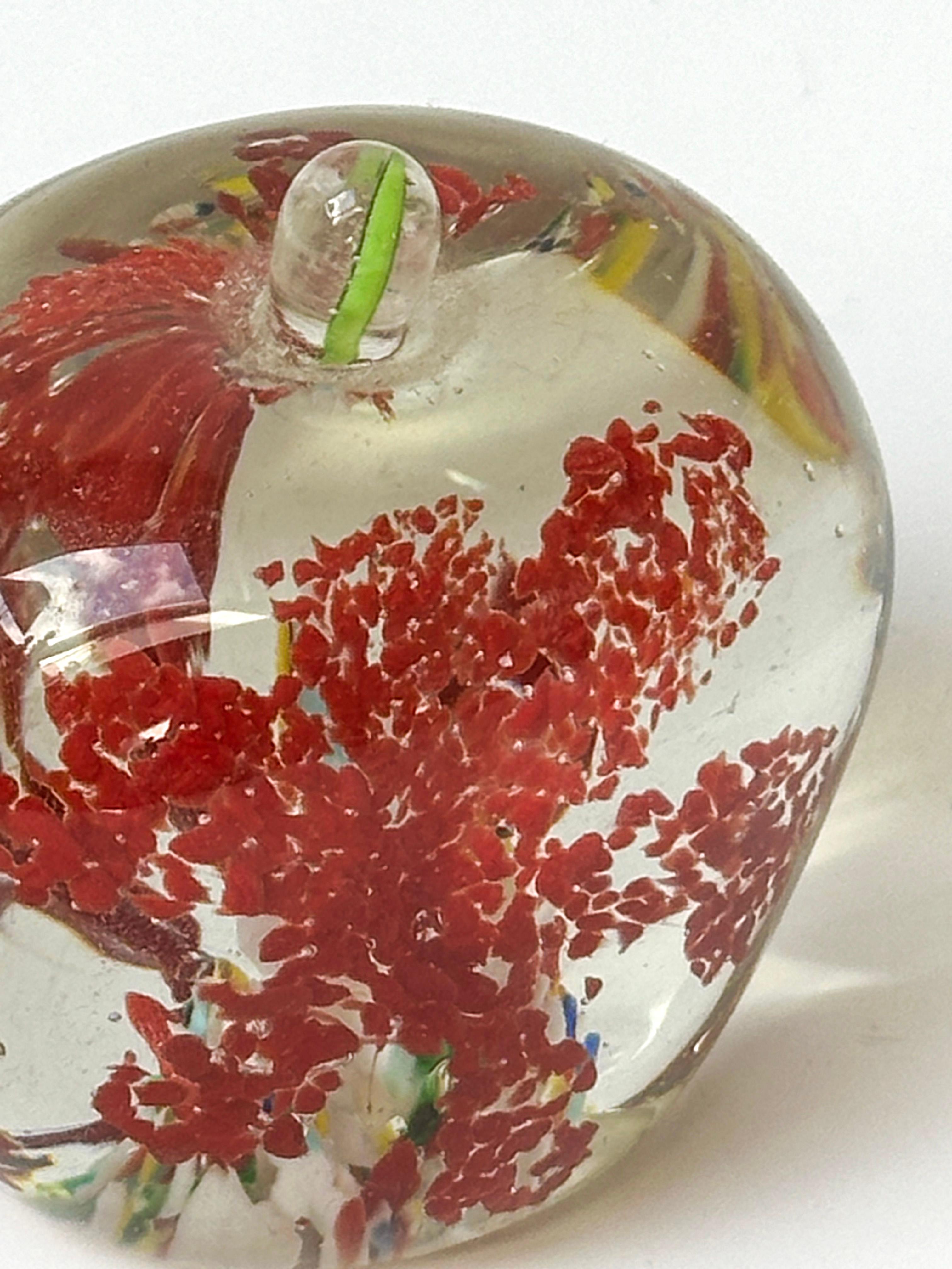 This vintage Murano glass paperweight, shaped in the form of an apple, showcases handcrafted skill and excellence with its intricate internal details and technical creativity. It exemplifies the glassblower's fine skills, displaying a captivating