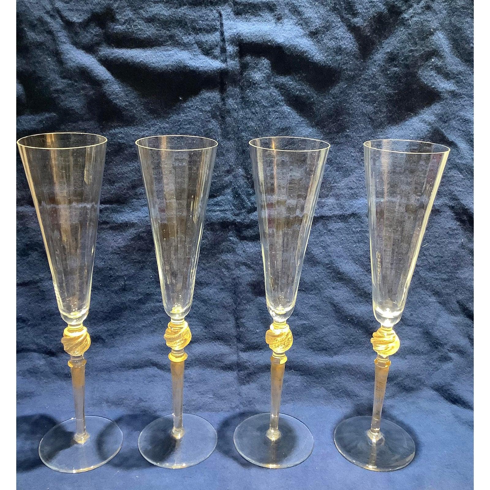 Set of 4 custom murano glass champagne flutes from the 1970s. These are clear glass with a lot of 24-karat gold flakes. The clear glass is smooth on the outside and rippled on the inside.
These are still being produced as 10 inch high flutes and