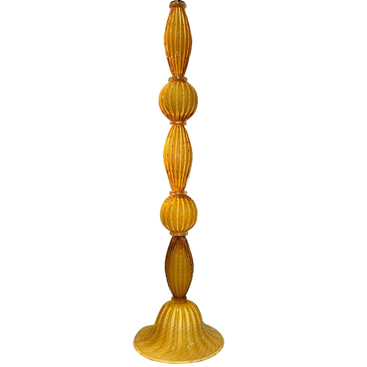 Lámpara italiana de vidrio soplado de color ámbar dorado de hacia 1960.

Medidas:
Altura del cuerpo: 59
Altura hasta el apoyo de la sombra  71