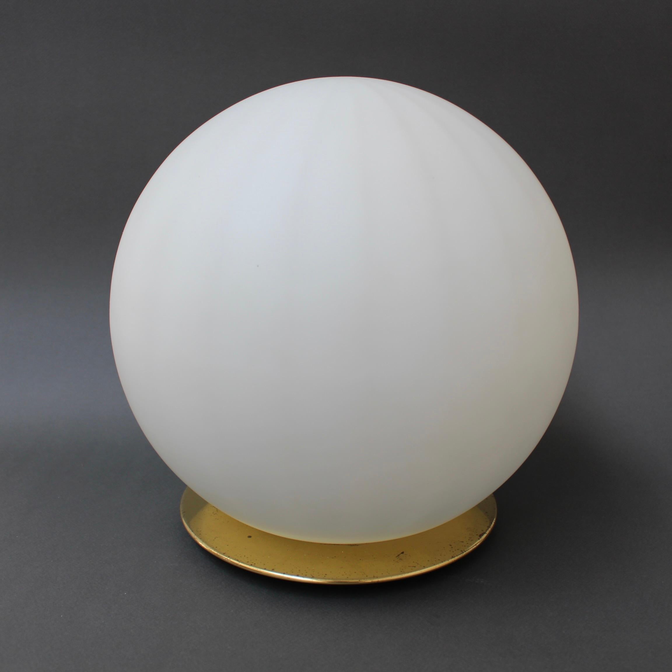 A 1970s Italian Murano glass globe table lamp. Modernist and elegant, this blown Murano table lamp provides a source of lighting which is both utilitarian and decorative. The subtle longitudinal lines both capture and amplify the light's interaction