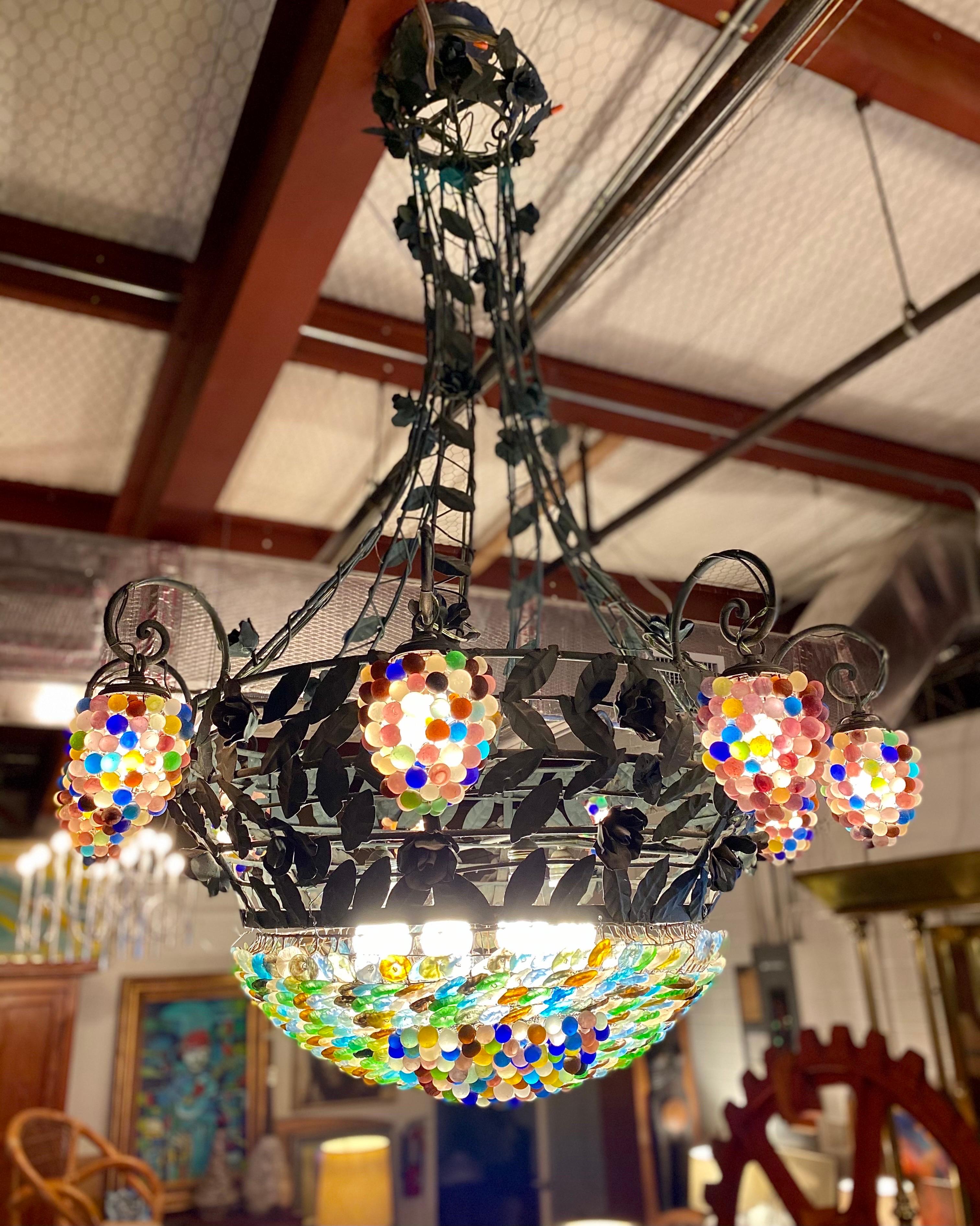 A stunning Italian 9-arm chandelier with multi-colored Murano glass grapes features a bowl base with multi-colored glass flowers and grapes while hanging from a metal frame that resembles vines with metal flowers and leaves painted in green. This