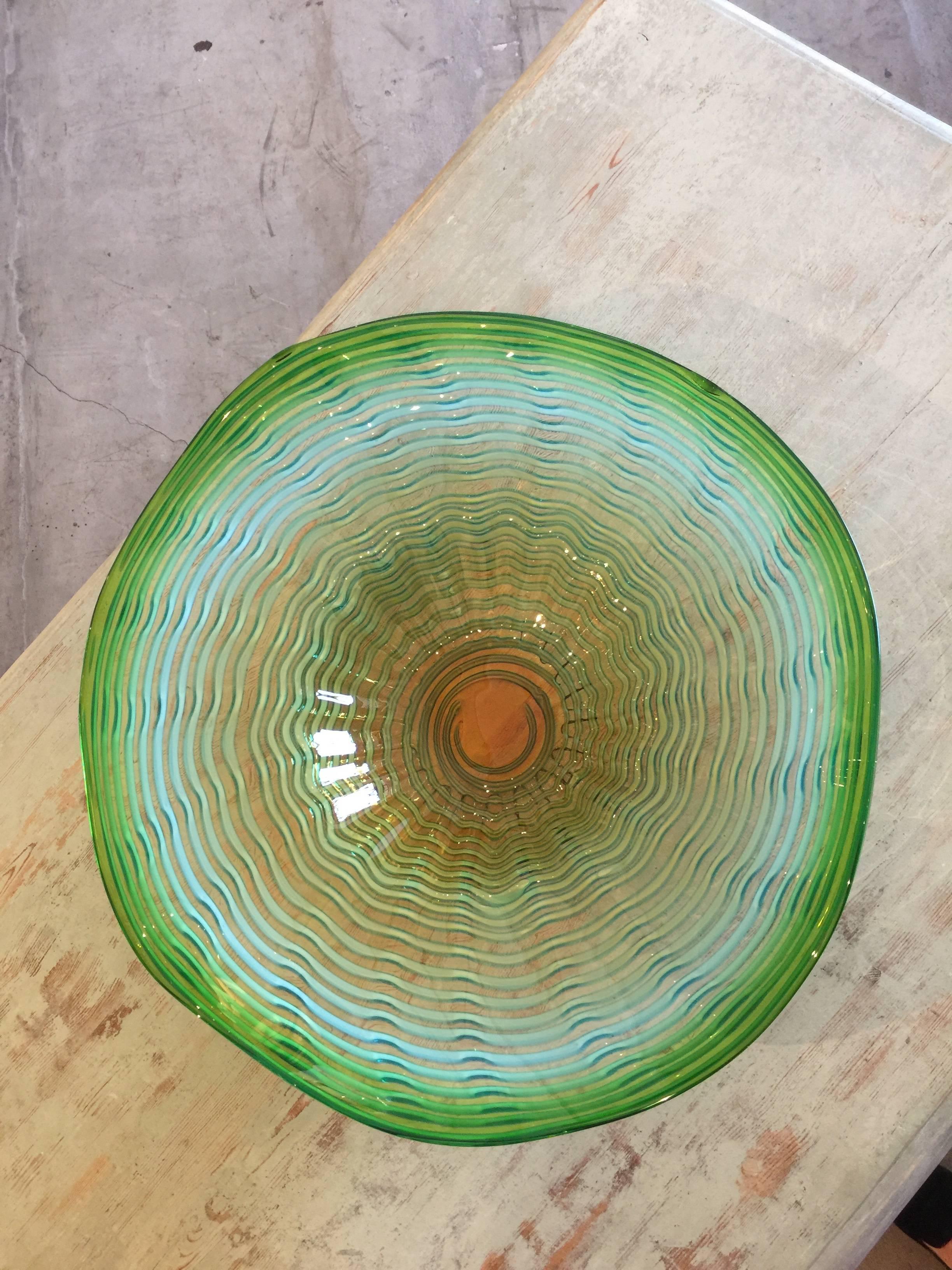 Vibrant colors of greens, blues and corals show through this free formed and raised ridges bowl.

Measures: D 19.25'', H 5.75''.
 