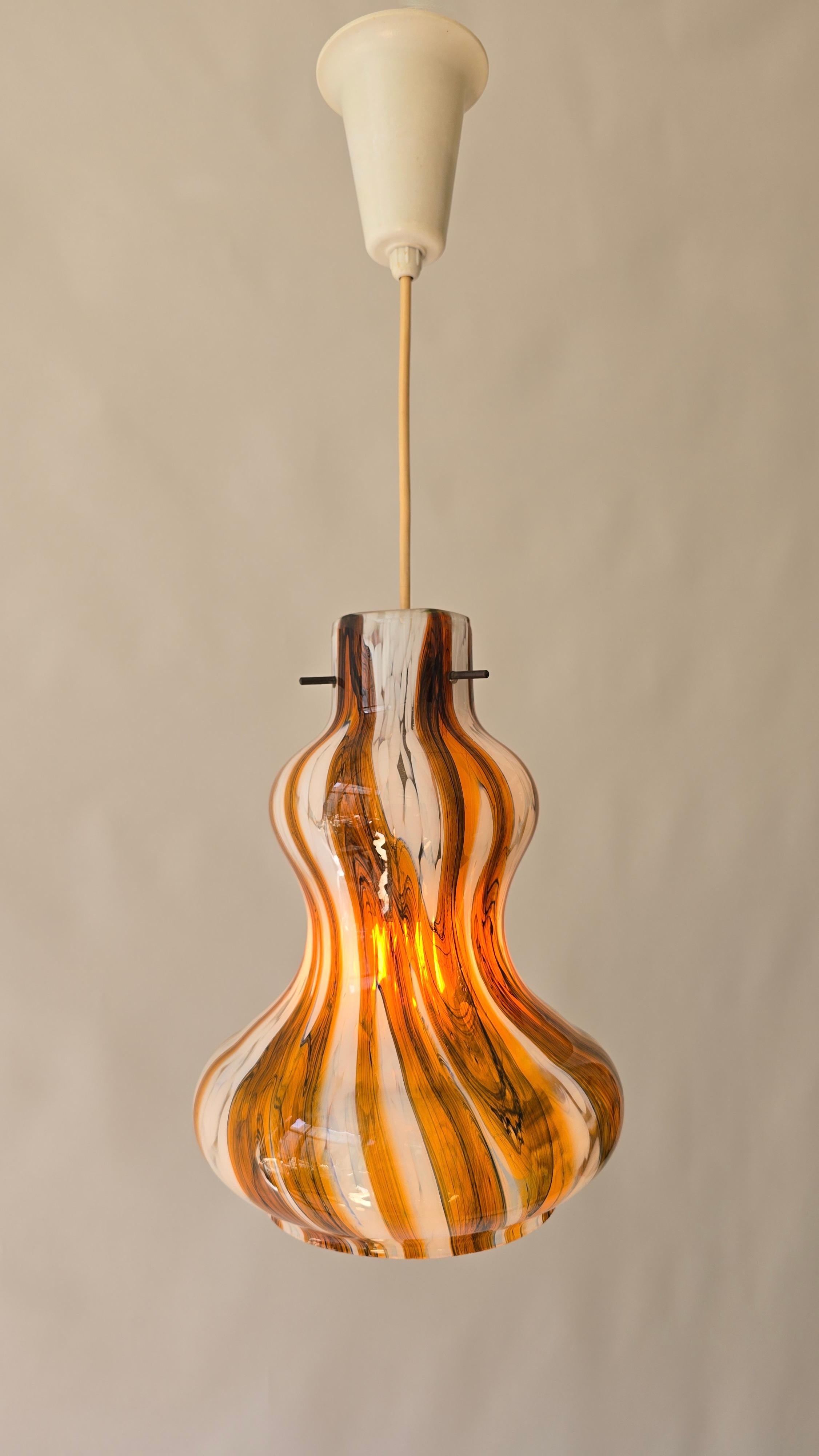 Lámpara colgante vintage de cristal de Murano con remolino ámbar y blanco, Italia, años 60

Lámpara colgante escultural de cristal de Murano fabricada en Italia en la década de 1960. La pantalla de cristal soplado a mano tiene una forma orgánica y