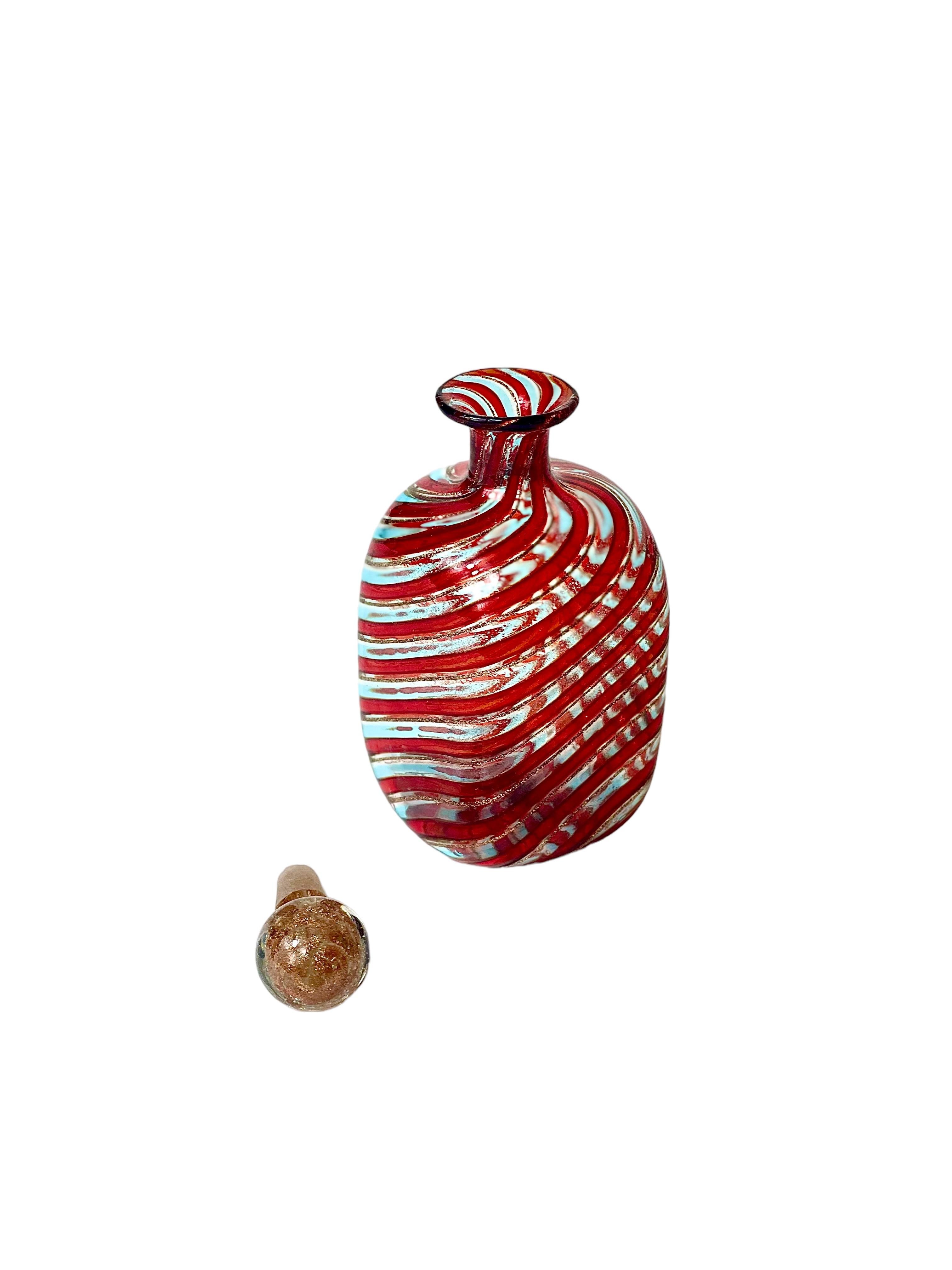 A very pretty vintage Italian perfume bottle, in Murano glass, featuring a striking cranberry and clear diagonal swirl pattern all around. The petite bottle is topped with its original spherical stopper, and the scent dauber is still present and