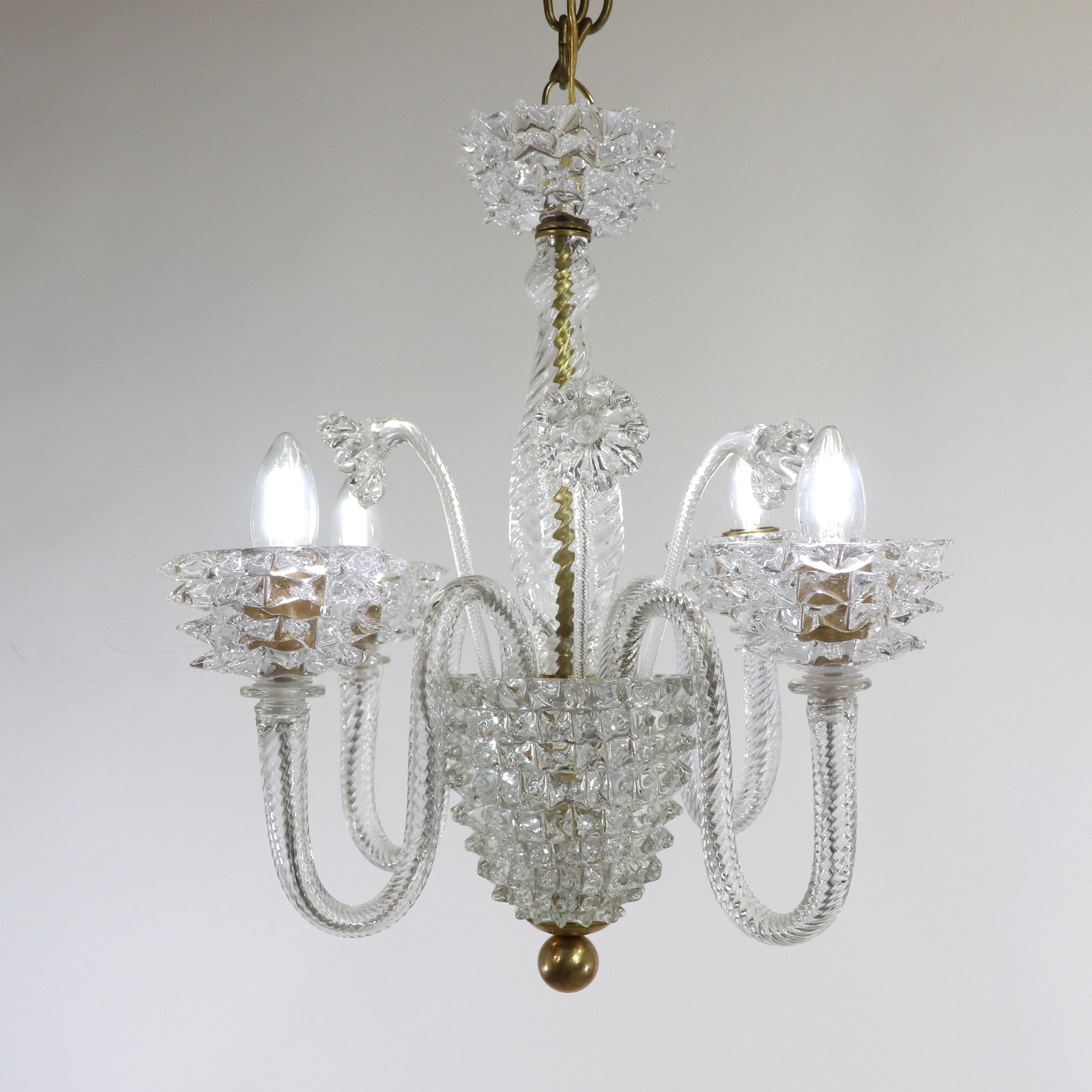 This sophisticated mid-century Murano chandelier has four undulating scroll arms and features rostrato detailing in the manner of Ercole Barovier. The fixture is stylized with glass flowers sprouting from the bulbous center column. The body and arms
