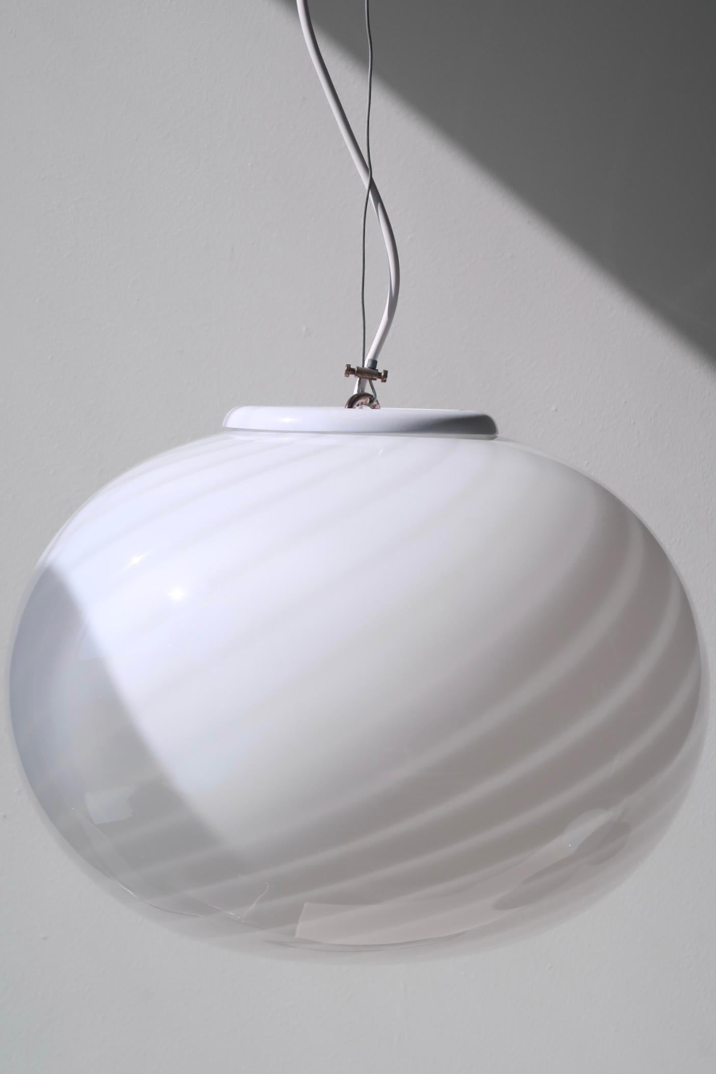 Vintage Murano pendant ceiling lamp in white glass. The glass is hand-blown in an oval shape with a beautiful swirl pattern. Handmade in Italy, 1970s, and comes with original label and adjustable suspension. D:35 cm H:25 cm (glass)

