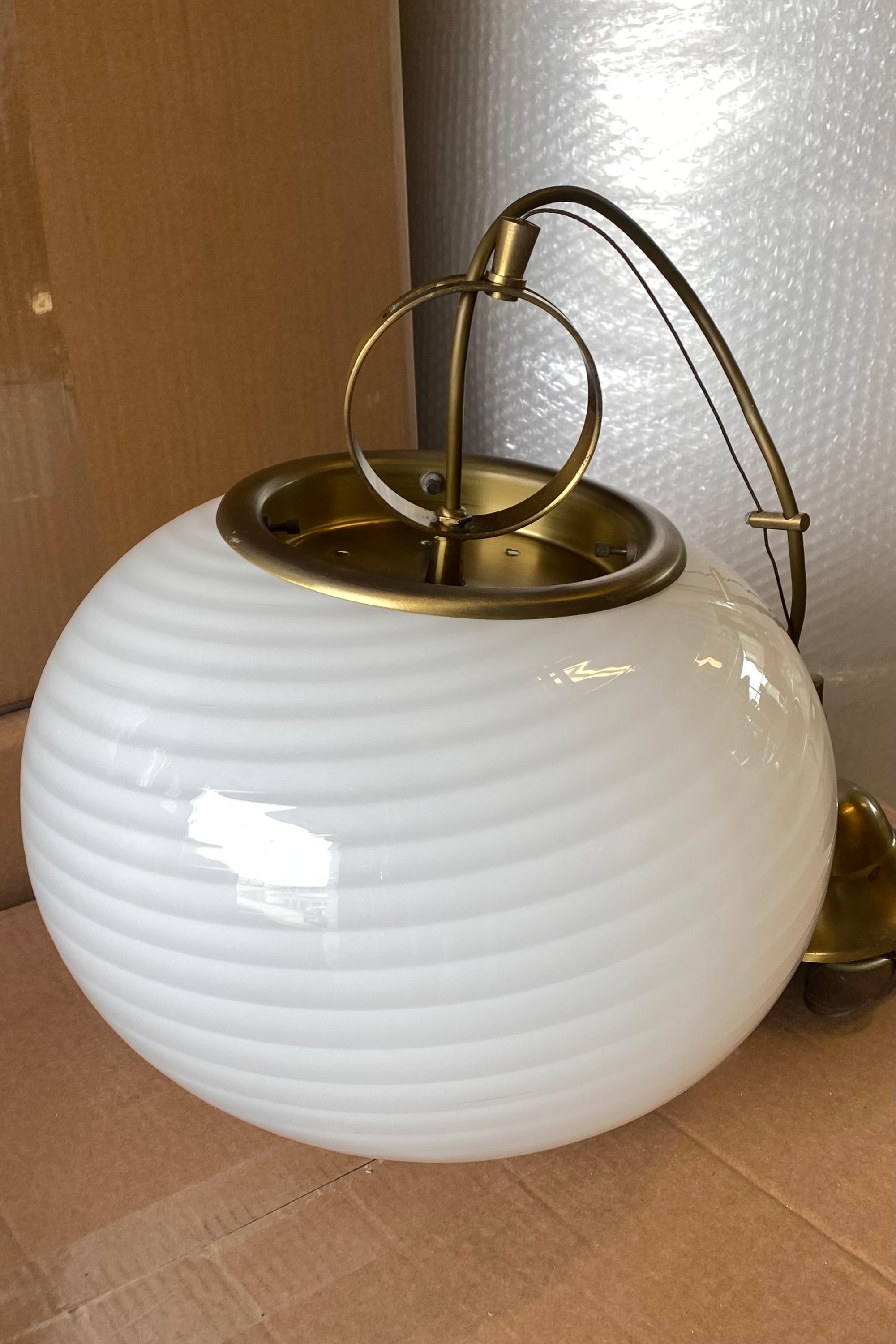 Vintage Murano pendant ceiling lamp in white opaline glass. The glass is mouth-blown in an oval shape with a beautiful swirl pattern. Handmade in Italy, 1970s, and comes with original adjustable suspension in patinated brass. D: 34 cm H: 25 cm