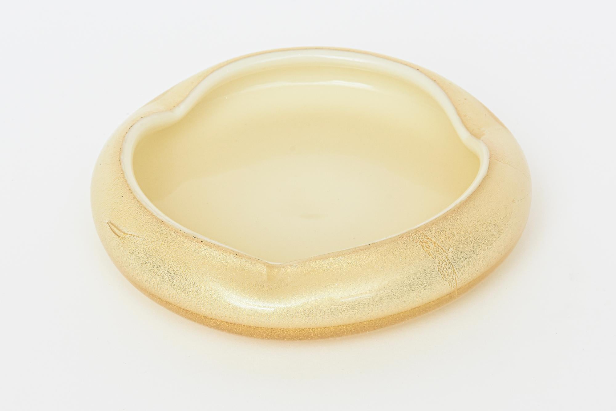 This low vintage Italian Murano hand blown bowl is by Archimede Seguso and is mid century modern. It has abundant gold aventurine and reads cream and gold with a white rim. It has 3 indented sides. In the interior it has a creamy interior. Great for