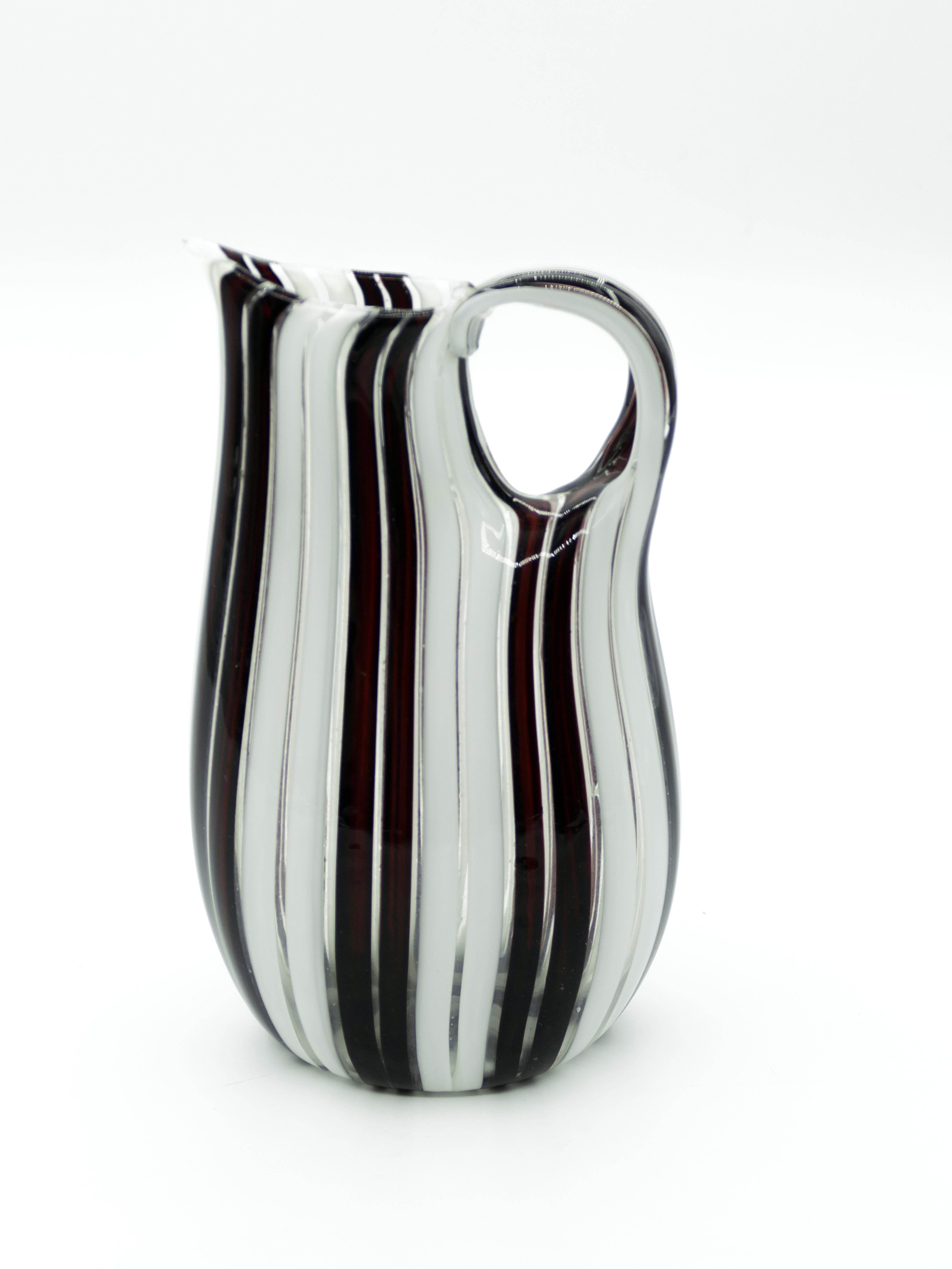 Murano striped vase is a beautiful glass decorative object with a handle, realized in the second

Half of the 20th century and of Italian manufacture. 

This valuable Murano glass object, carafe-shaped, oval stand, flat body, has the peculiarity