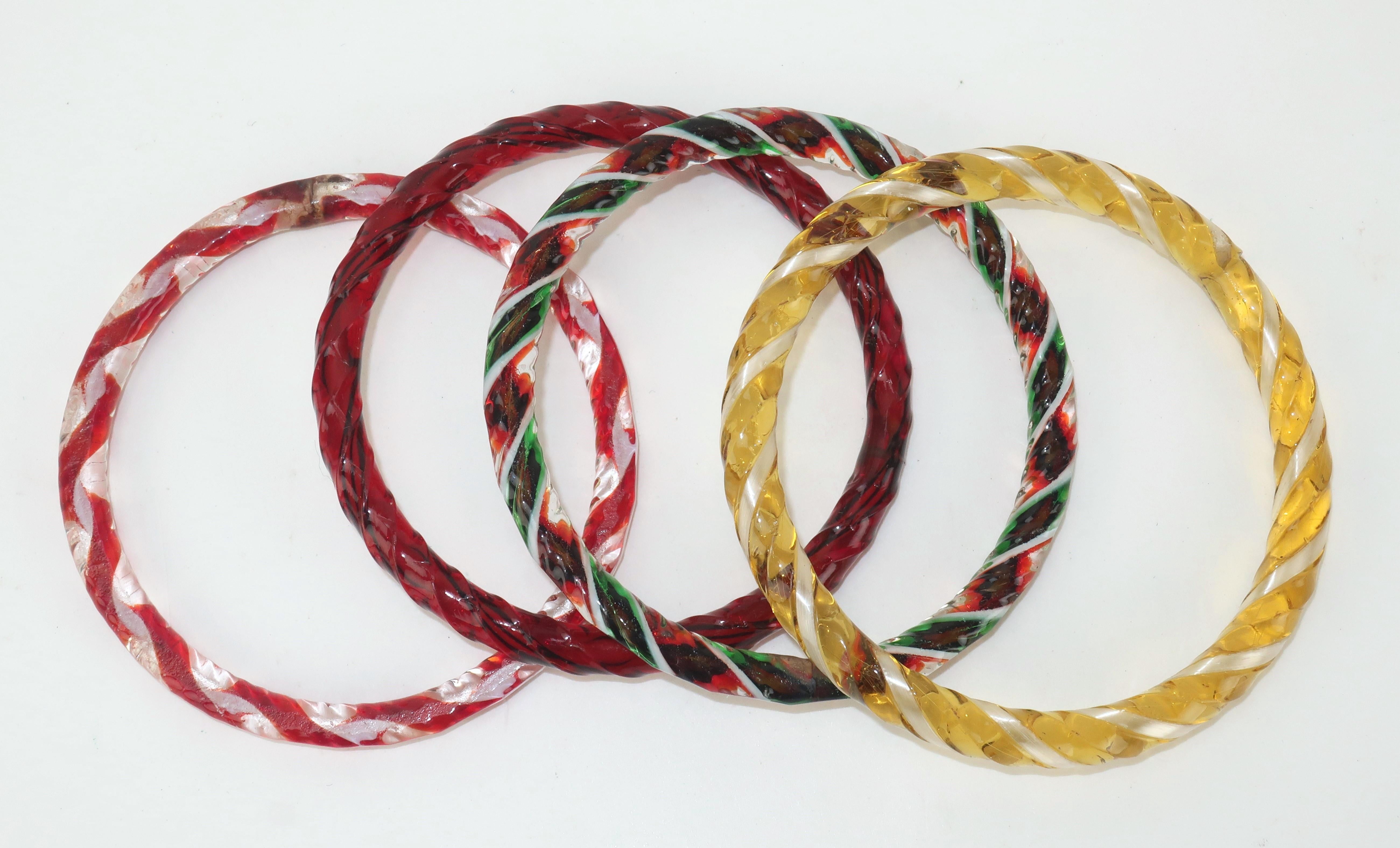 Satz von 4 Murano-Glasarmbändern im Vintage-Stil in Zuckerstangenfarben, darunter rot, gelb, grün und weiß.  Jedes Armband hat eine gedrehte Oberfläche und ein durchscheinendes Aussehen.  Wenn sie zusammen getragen werden, erzeugen sie einen