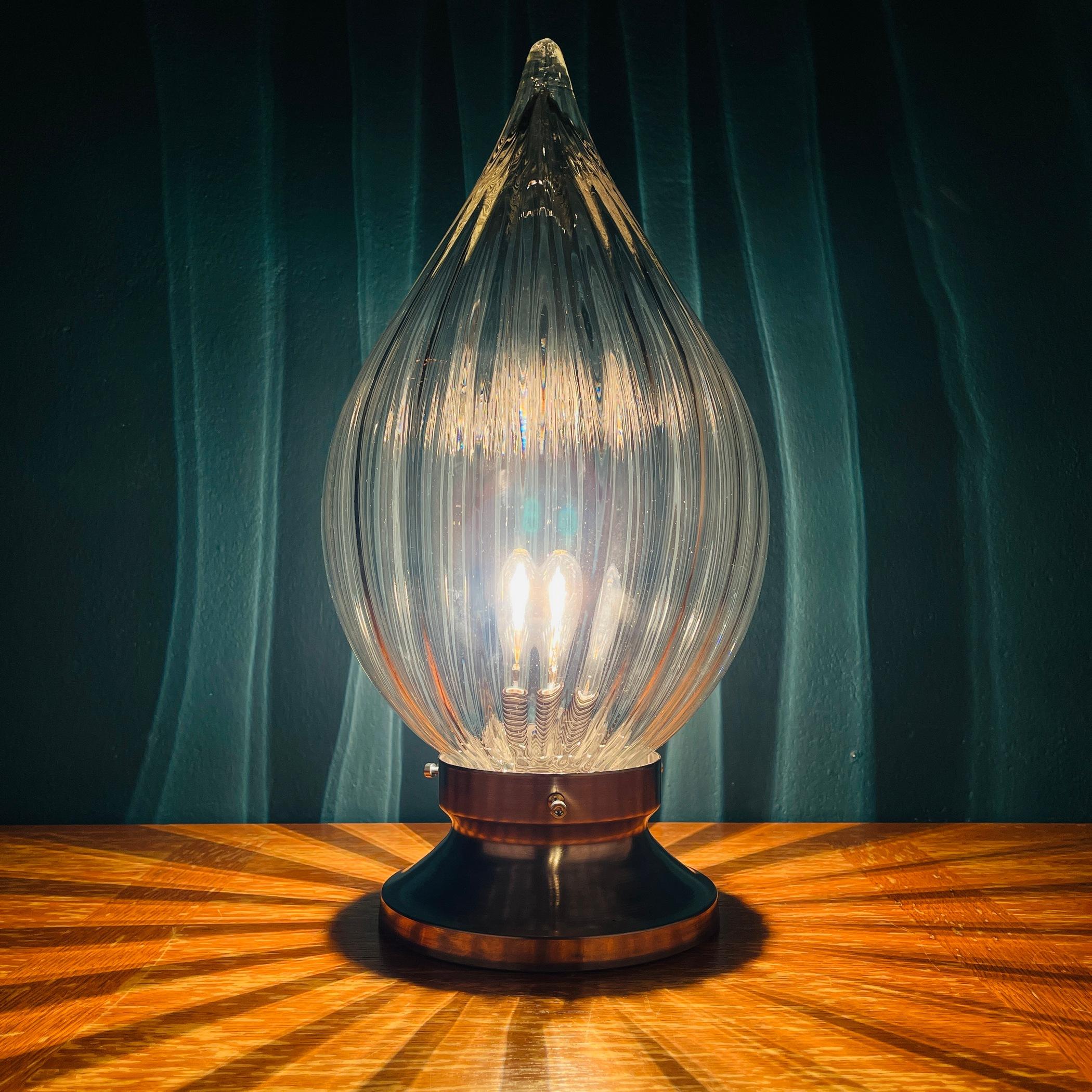 La très belle lampe de table en verre de Murano fabriquée en Italie dans les années 1970. L'abat-jour en forme de bougie en verre épais de Murano réfracte magnifiquement la lumière, créant un éclairage unique. Excellent état vintage. Une ampoule E27