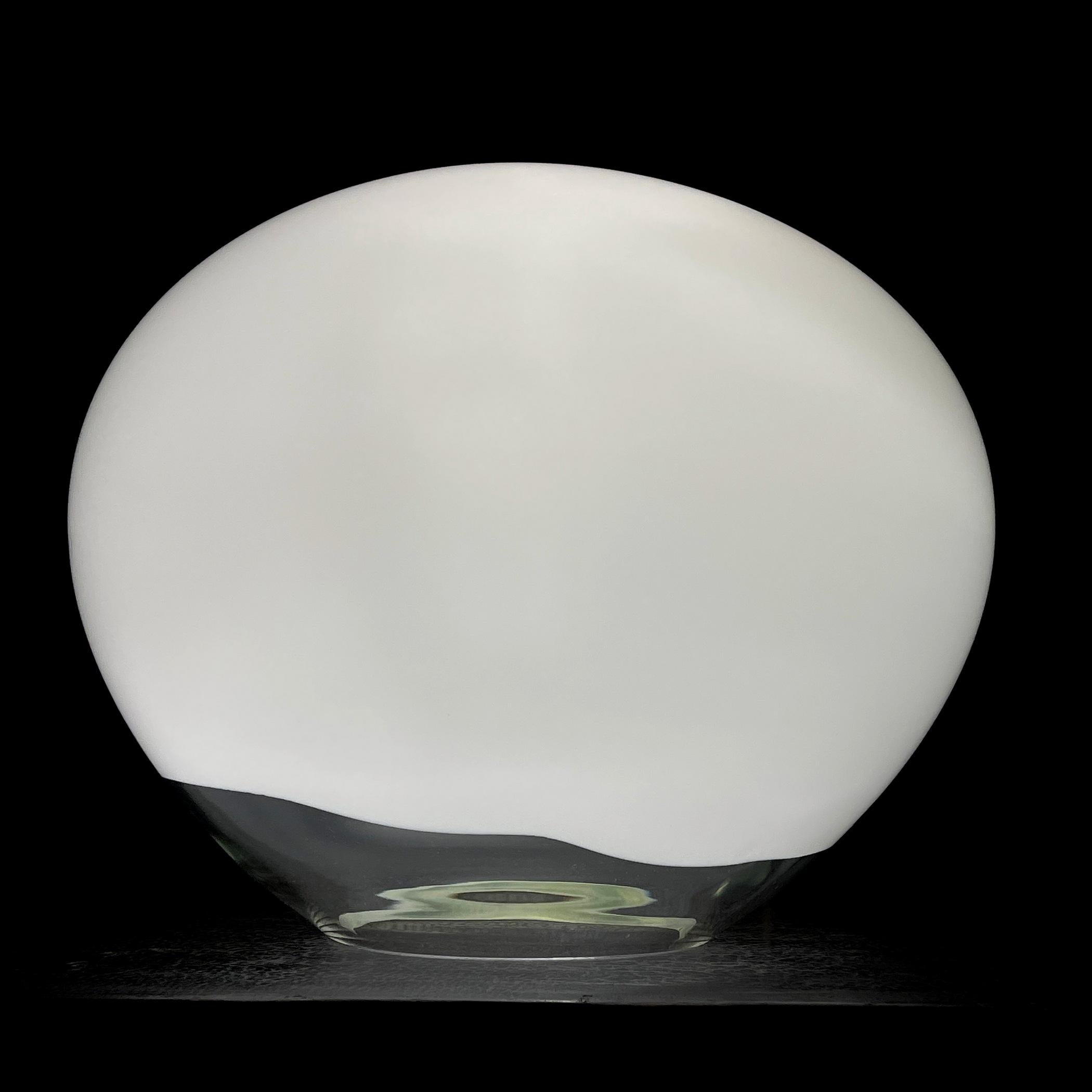 Discover the unique design of the Nessa table lamp, which captivates with its exquisite beauty and unconventional style. Handcrafted from various shades of Murano glass, this lamp visually resembles an elongated circle. The distinctive flattened