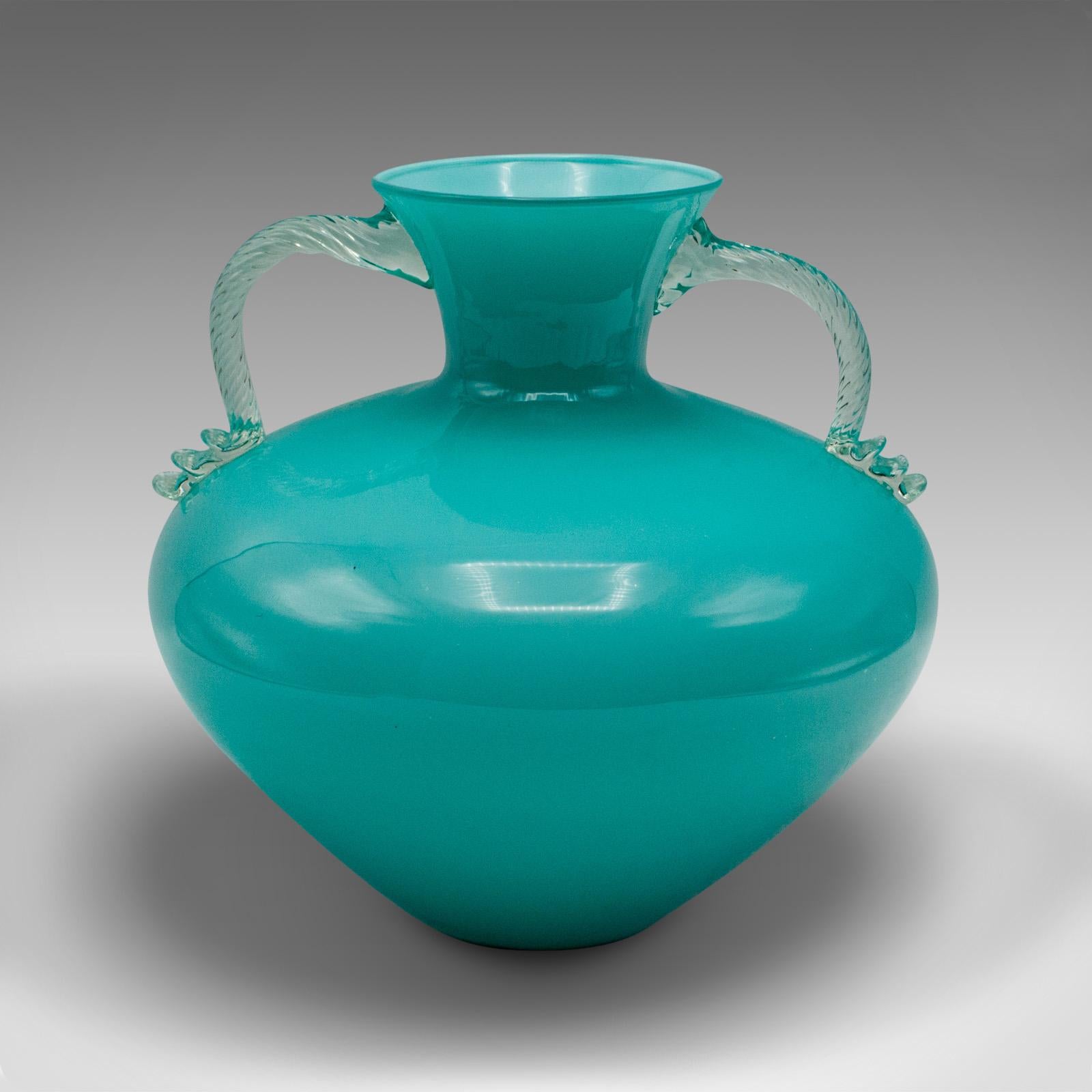 Il s'agit d'un vase vintage à deux anses de Murano. Un balustre décoratif italien en verre d'art, datant du milieu du 20e siècle, vers 1960.

Une couleur frappante avec une proportion délicieuse et un attrait esthétique
Présente une patine d'usage