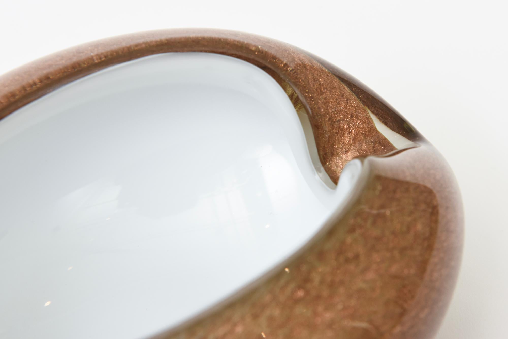 This vintage Italian Murano glass bowl is almond shaped white cased with copper and gold aventurine explosions throughout . Great as a serving bowl, barware, ashtray or catchall. From the 60's. Cinched on both ends. The height to the highest point