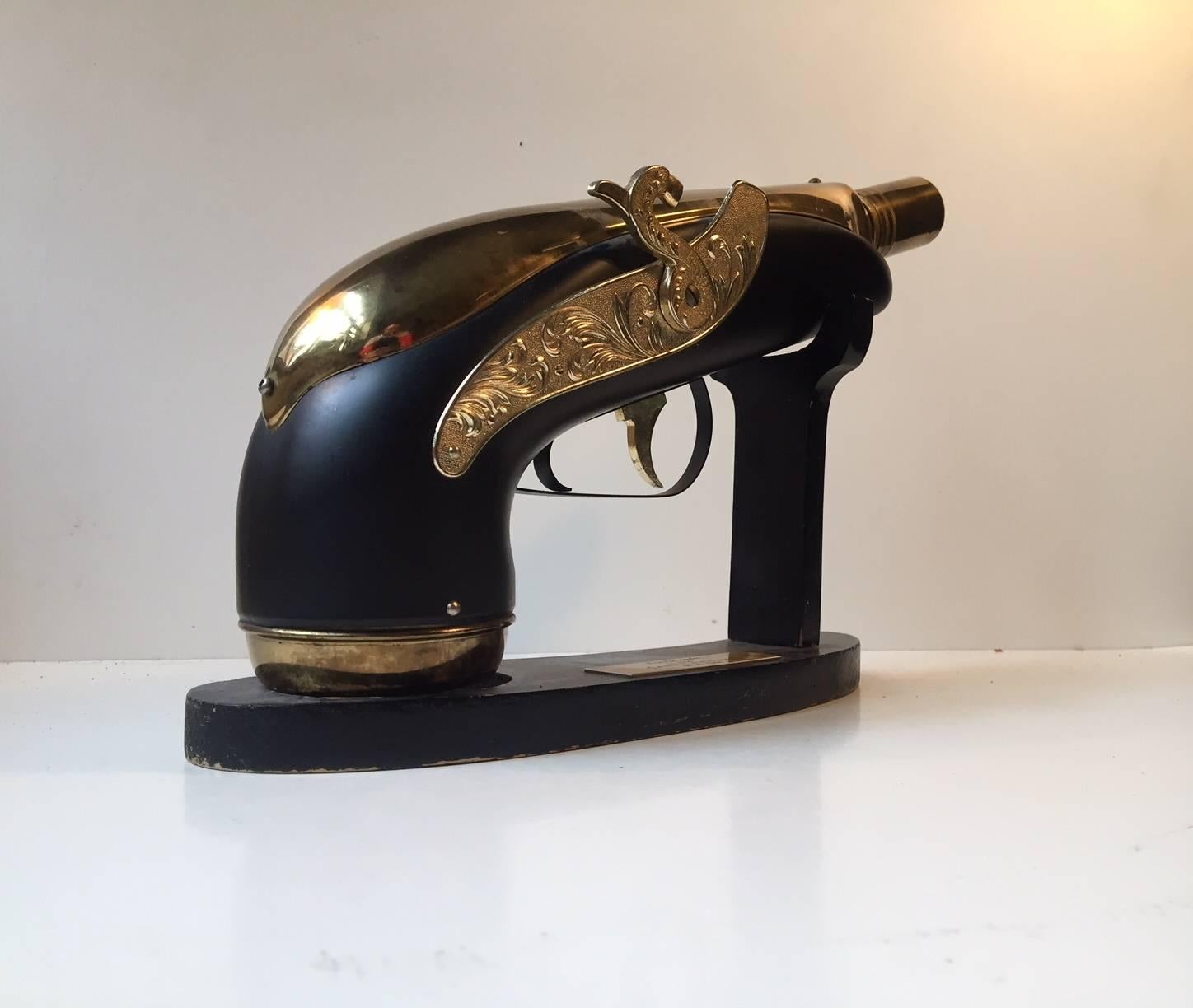 This novelty piece was given as a gift in 1964 to the manager of a Danish company called Carl Leervad by the employees. It’s a vintage blunderbuss musical gun decanter. When you take the gun decanter off its stand, it plays 