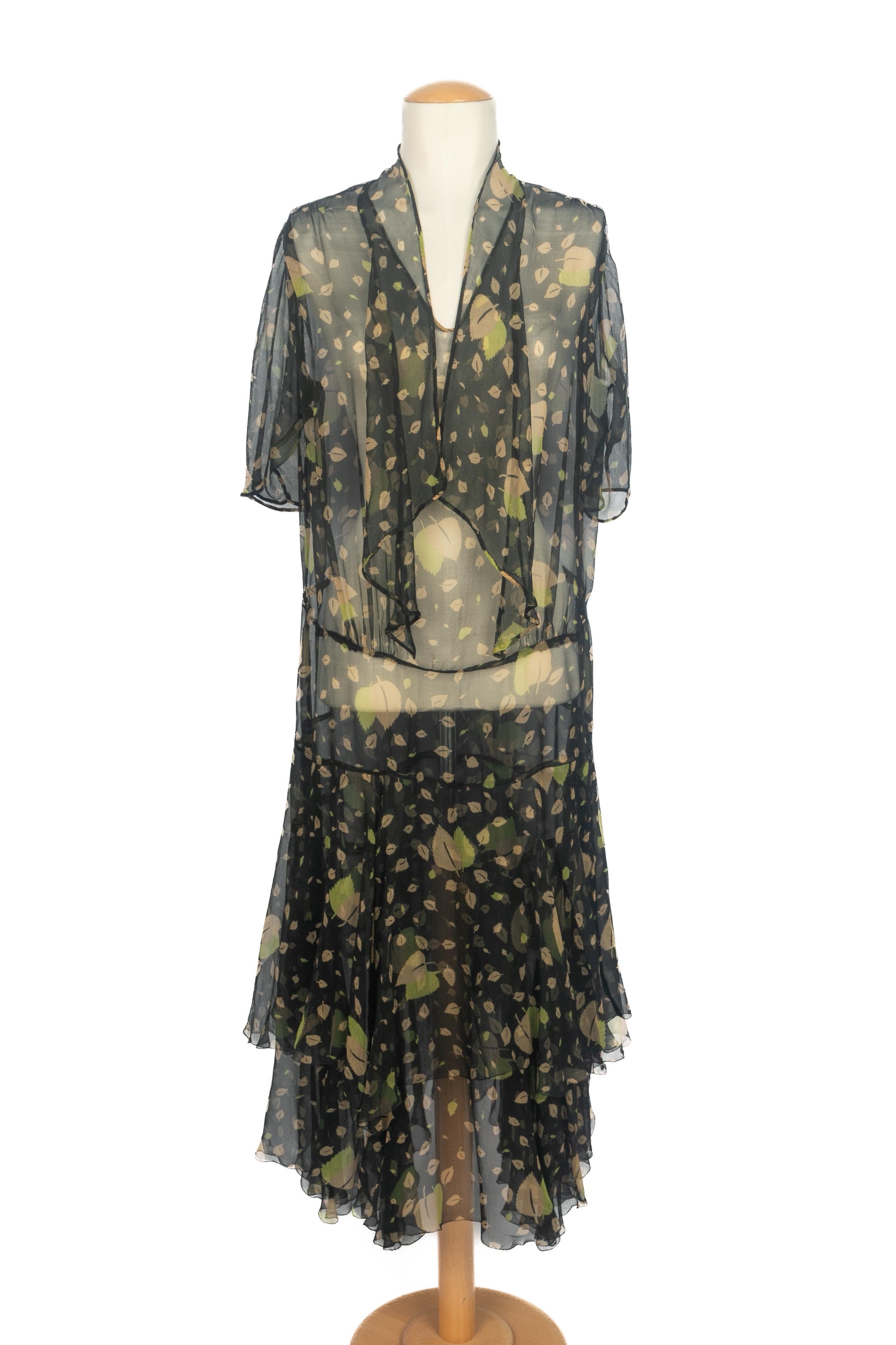 UNBEKANNT - Transparentes schwarzes Musselin-Kleid mit einem beige-grünen Blattmuster. Keine Größenangabe, es passt eine 36FR/38FR/40FR.

Bedingung:
Guter Zustand

Abmessungen:
Schulterbreite: 38 cm - Brustumfang: 50 cm - Ärmellänge: 44 cm - Länge: