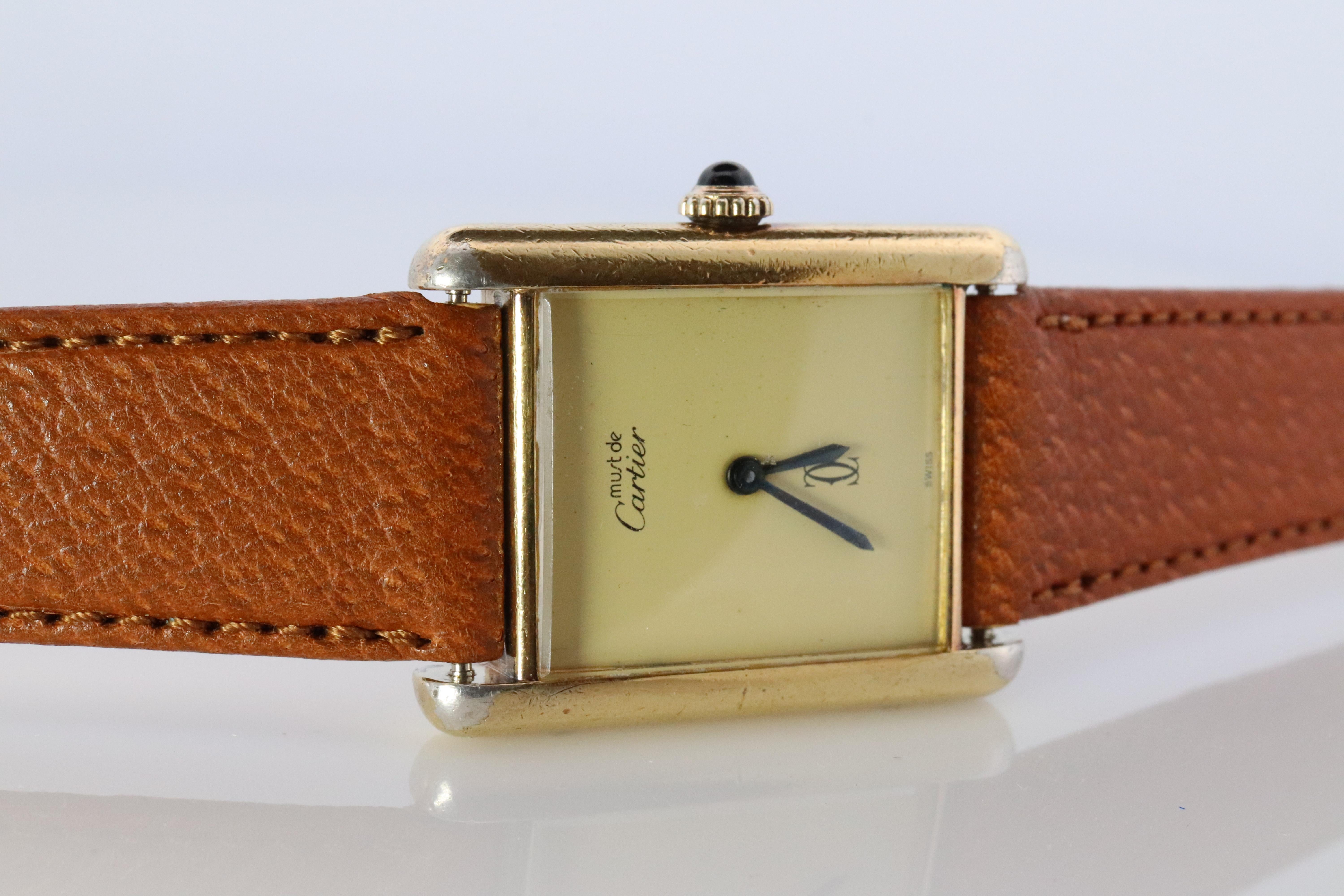 Echte Cartier Uhr. Vintage Iconic Tank Argent. Sterling Silber und vergoldet (Vermeil). 

Kommt mit einem neuen GUCCI-Lederband und einer Original Cartier-Schließe.

Seltene Champagne Mystery Dial mit mechanischer Handuhr.

Zustand: Hat einige