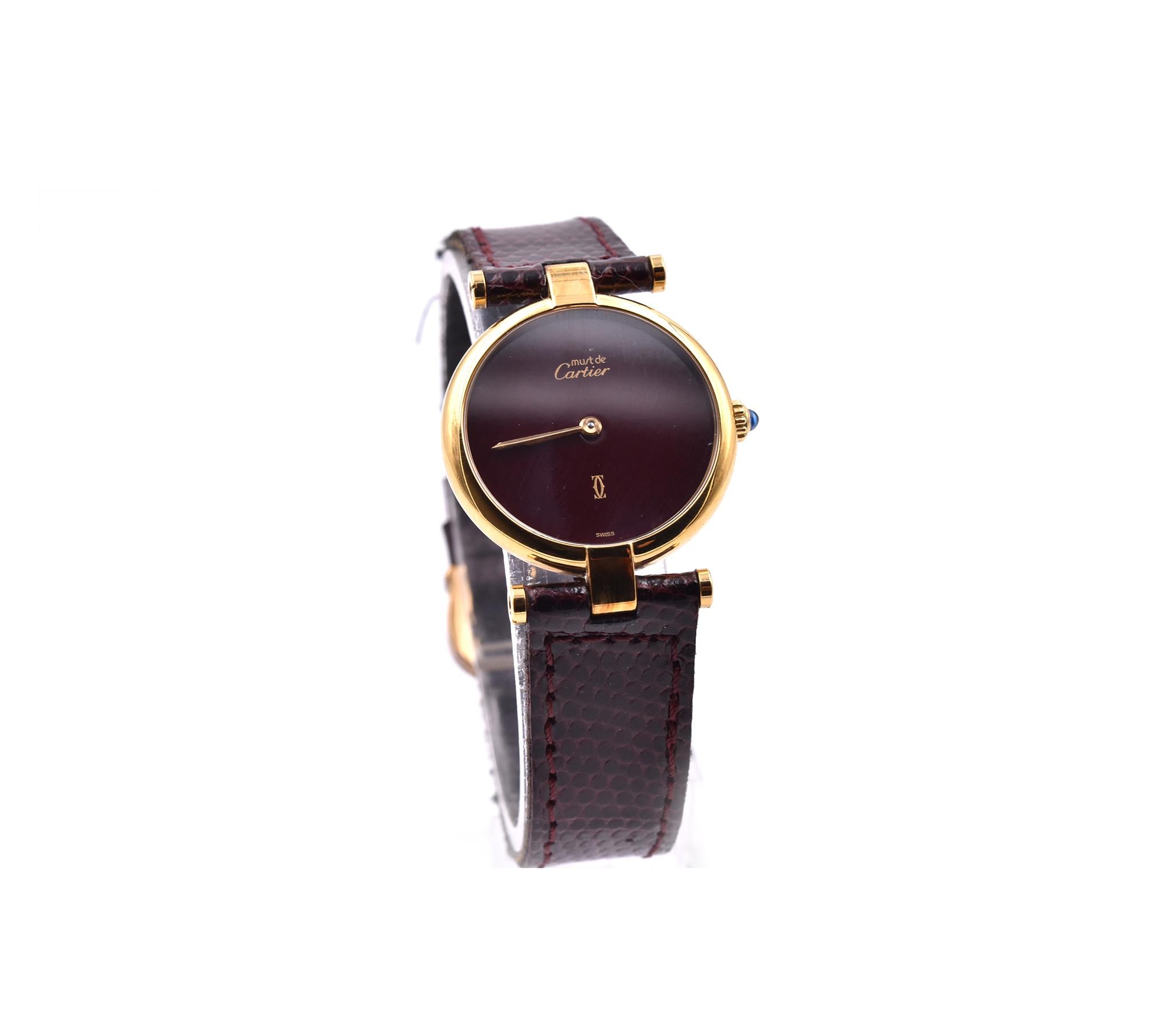 Movement: quartz
Function: hours, minutes
Case: 24mm vermeil yellow gold case 
Dial:  wine color dial, Roman numeral dial with gold hands
Band: black cherry lizard leather strap with tang buckle
Serial: 100XXX
Reference: Must de Cartier Argent