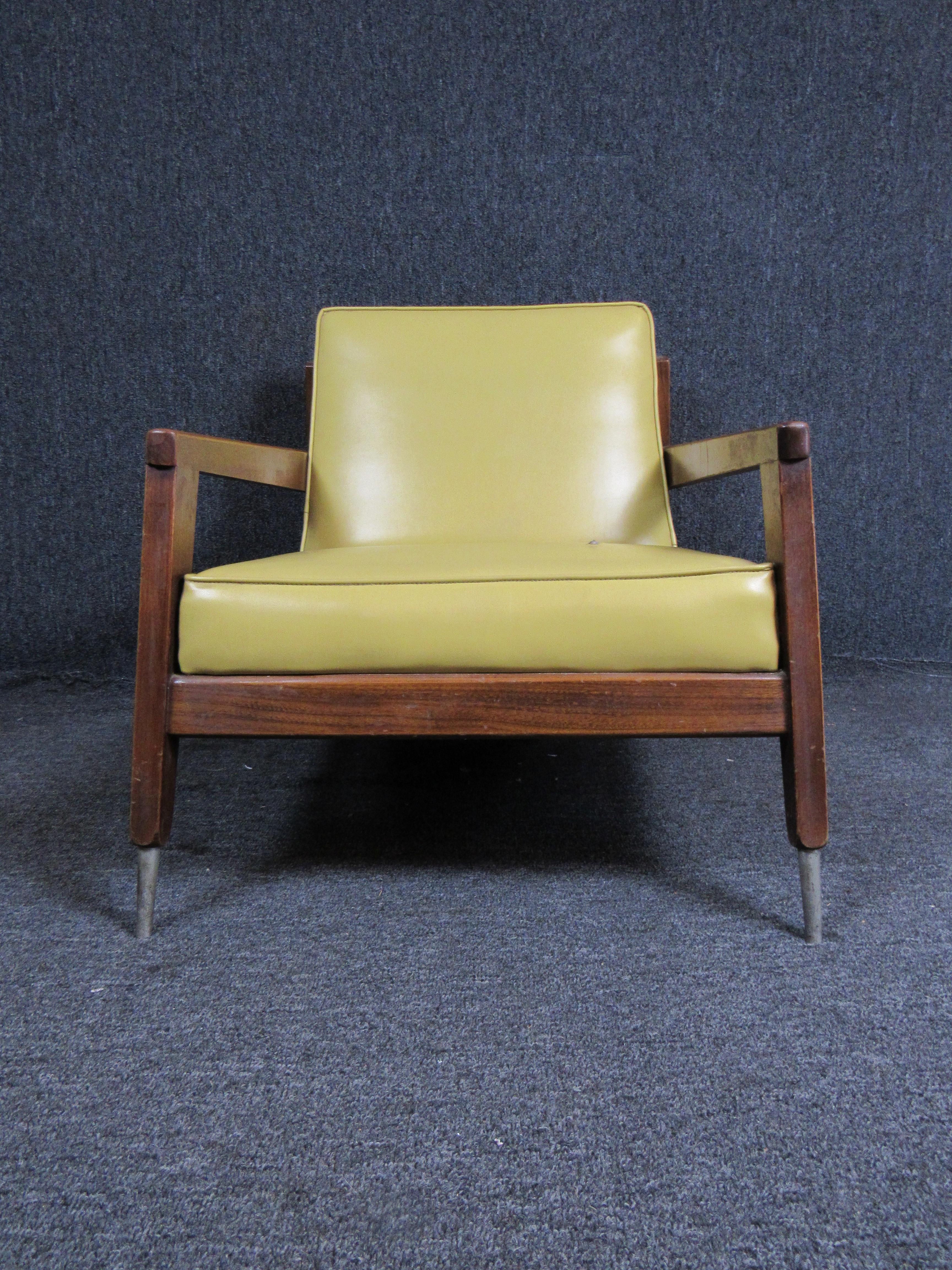 Bring home Classic Mid-Century Modern style with this bold vintage armchair. A sharp walnut frame contrasts perfectly with the retro mustard vinyl covering. An authentic, subtle patina completes the look. Perfect for the home or office. Please