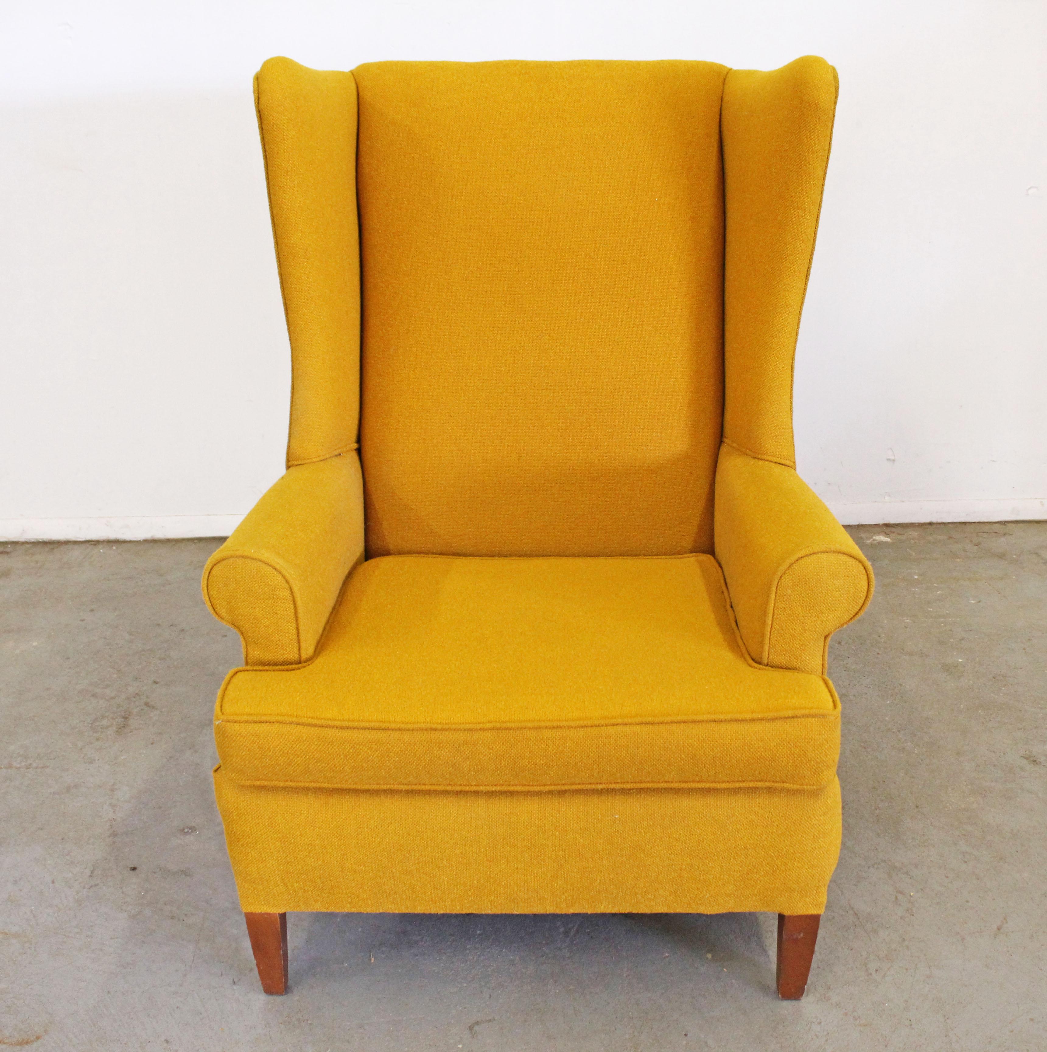 Offered is a vintage wing back chair with textured yellow upholstery and wood legs. It is in good condition with usable upholstery, only showing a slight stain on the back and minor scratches on the legs. It is structurally sound. A great, sturdy