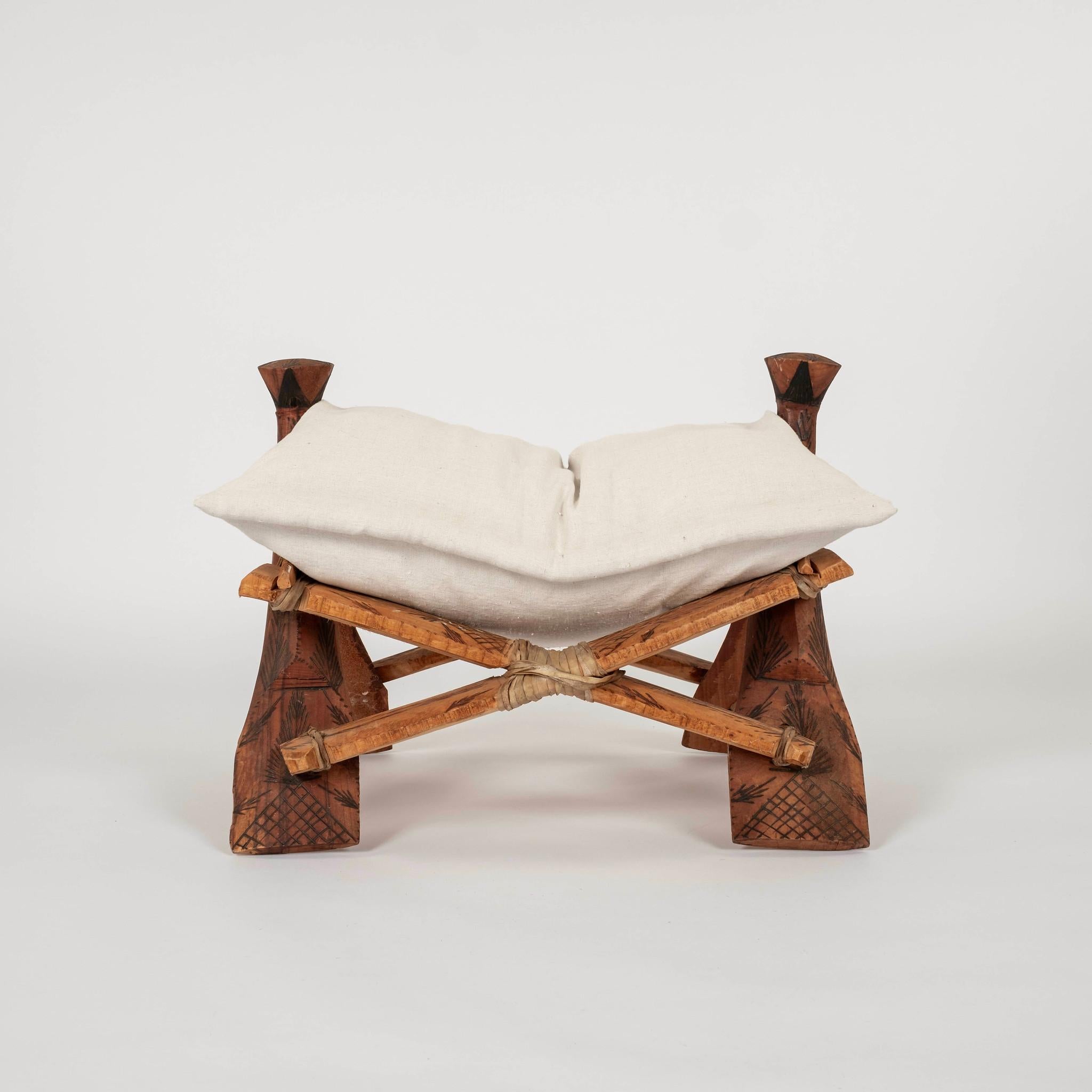 Tabouret vintage en selle de chameau d'Afrique du Nord ou du Moyen-Orient,  vers les années 1960. Ce magnifique tabouret en bois et cuir est gravé à la main de motifs tribaux nomades. Le coussin de siège est de fabrication récente

