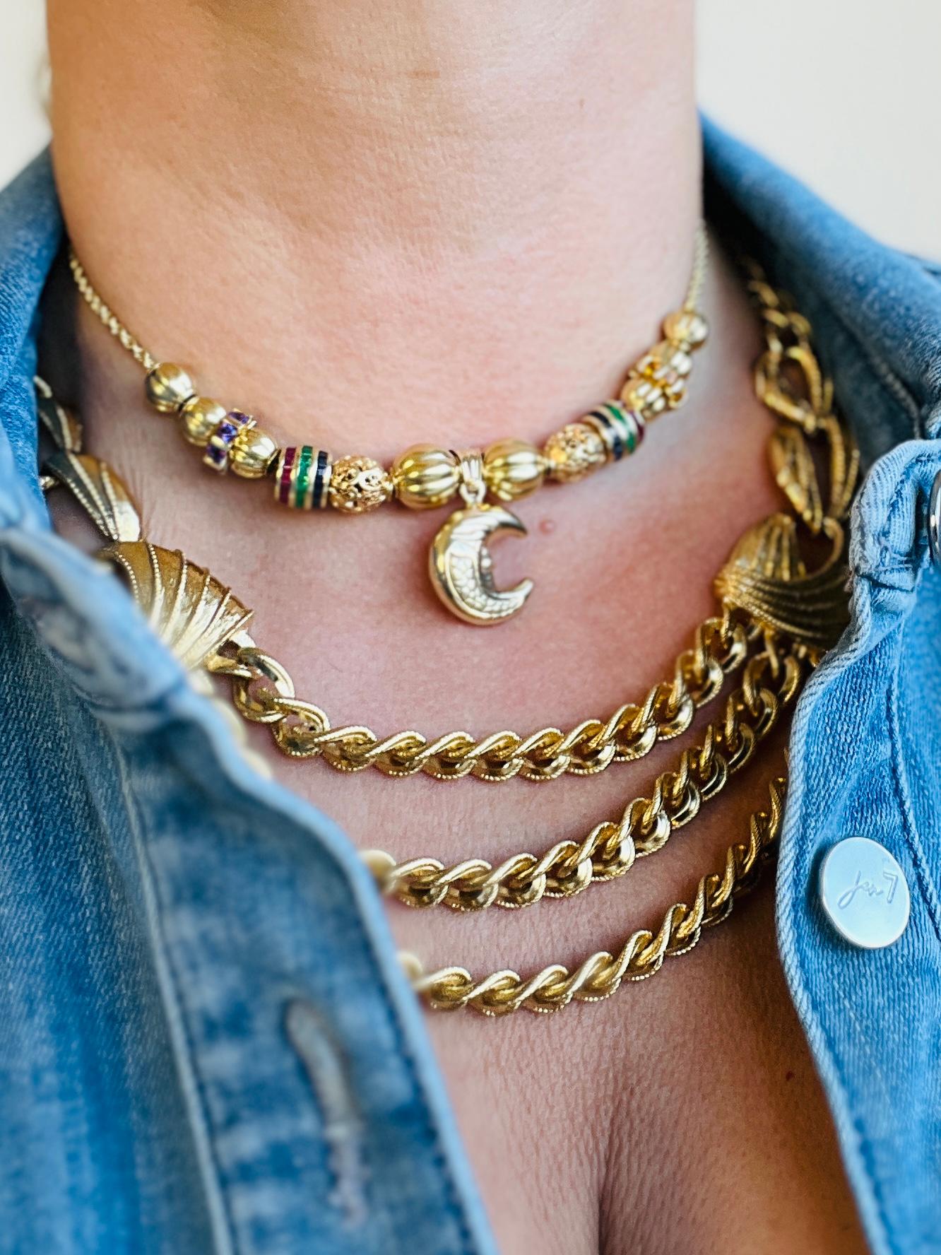 This weighty necklace showcases a blend of classic charm and modern elegance. At its heart lies a trio of curb chains, creating a tiered effect that drapes elegantly across the collarbone. Each chain is composed of flat, closely-set cable links that