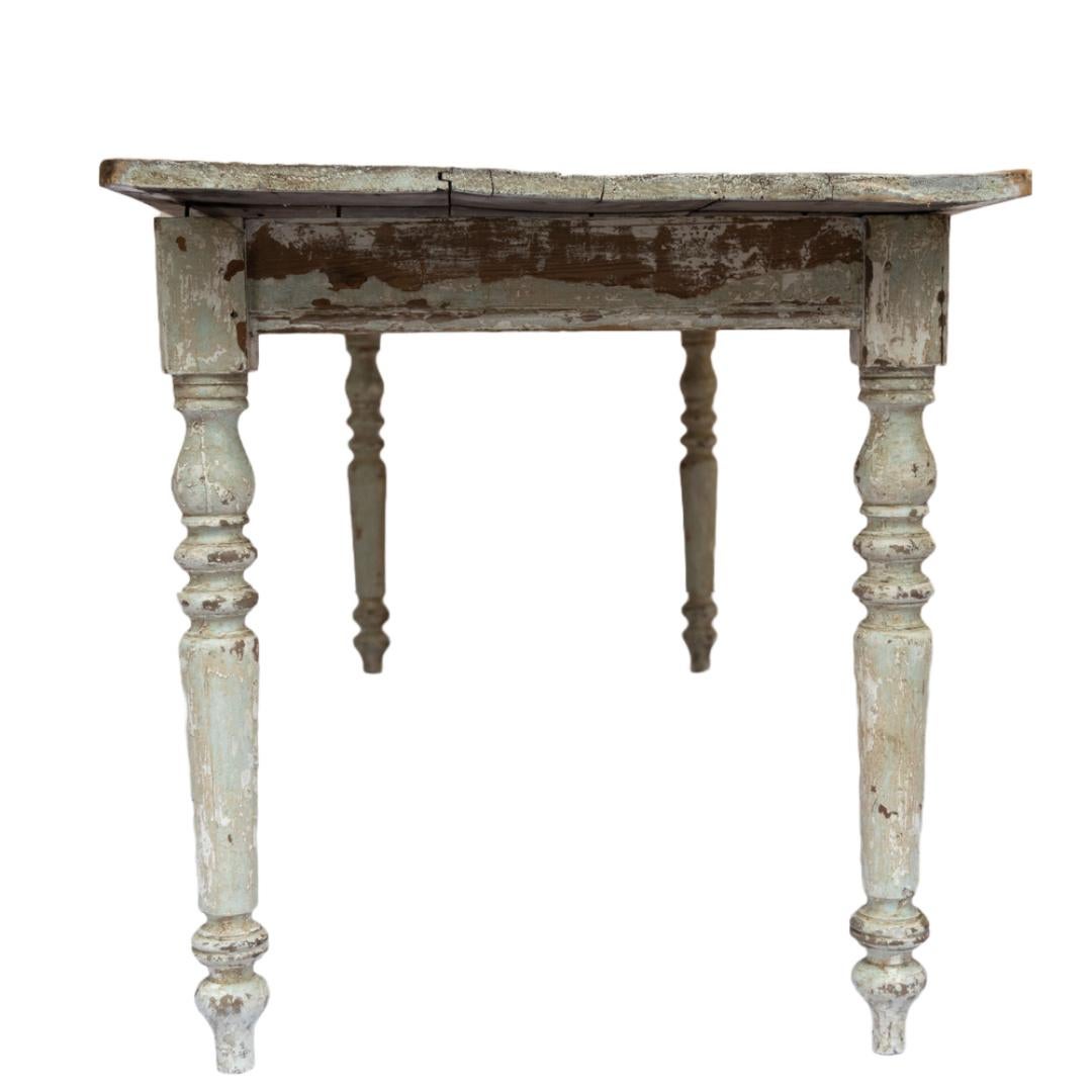 Cette table de ferme française du XIXe siècle est le fruit d'un excellent travail artisanal et d'une construction robuste. La finition des pieds tournés en blanc délavé et le riche plateau patiné ajoutent de la chaleur et du caractère, soulignant