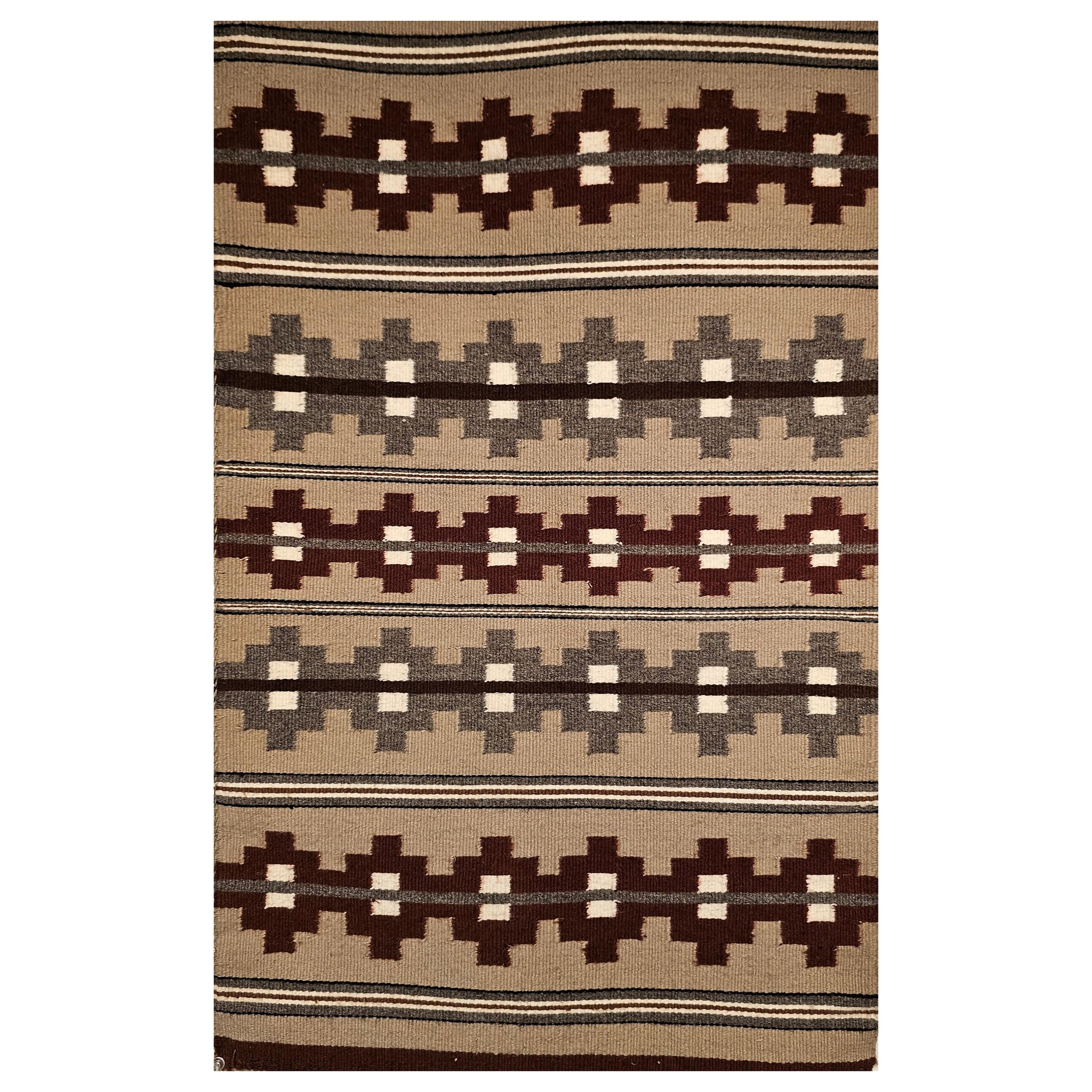 Esta alfombra navajo vintage del tercer cuarto del siglo XX, bellamente tejida, muestra un atrevido diseño de bandas y rayas en tonos cálidos y orgánicos. Grandes bandas geométricas en burdeos y gris se disponen sobre un suave fondo topo, acentuado