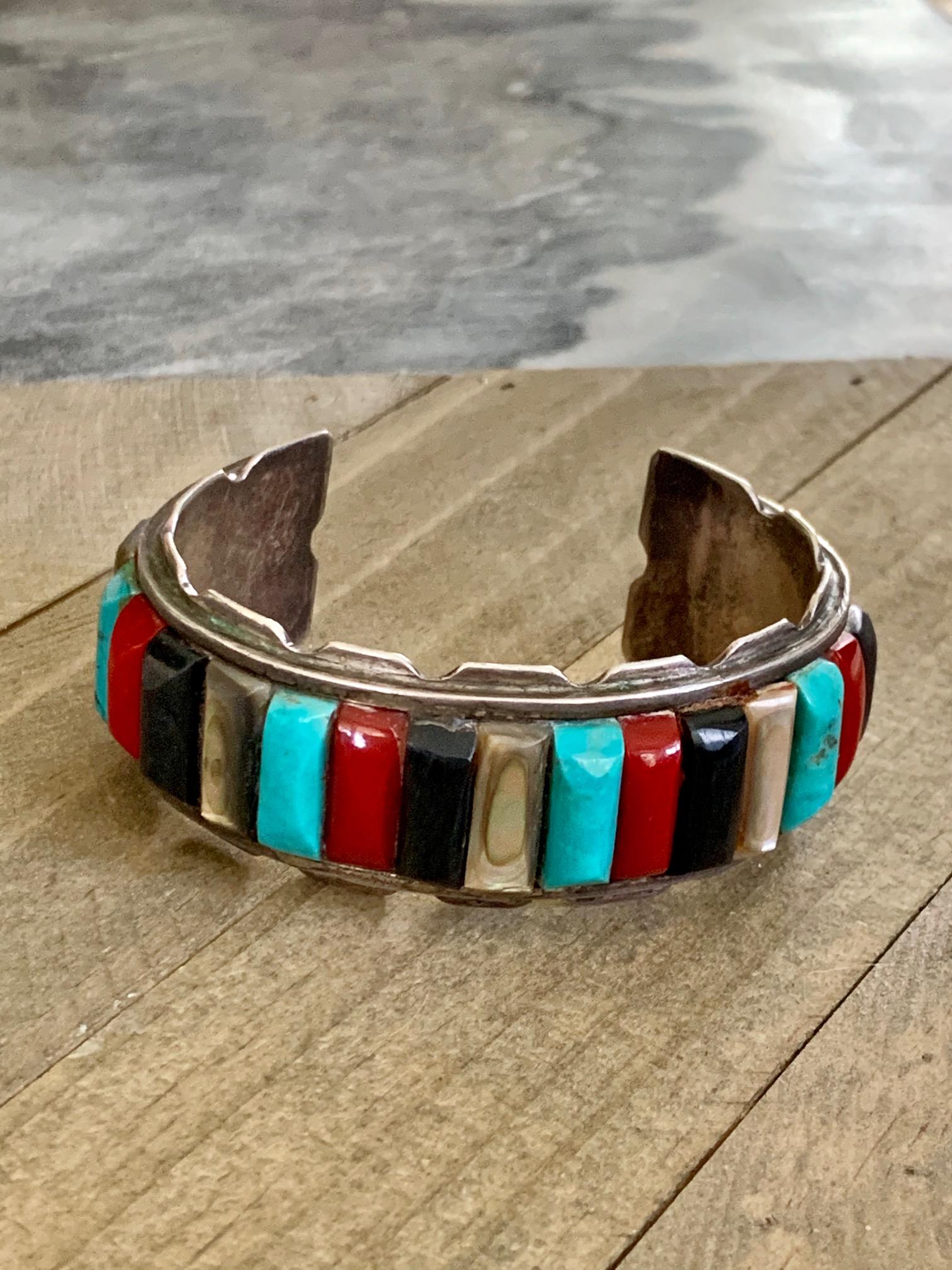 This beautiful Native American cuff bracelet features 23 multiple inlaid stones, including, Turquoise, Jet, Coral and Mother of Pearl.

The outside measures 8 1/4