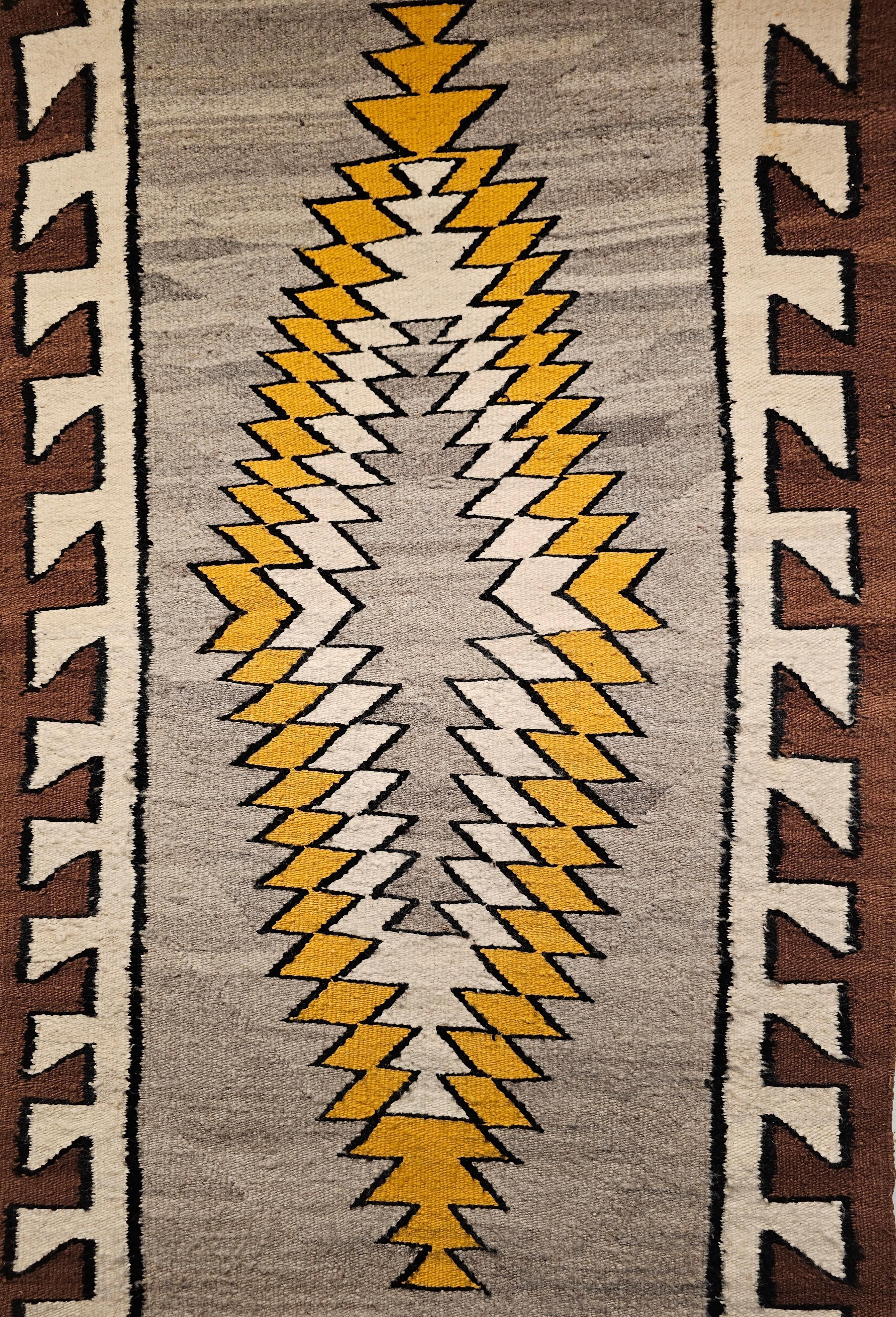 A beautiful Navajo area rug from the SW United States from the first half of the 1900s. The Navajo rug has a striking concentric triple medallion design in yellow, ivory and gray set on a silver gray background with a brown and ivory border framing