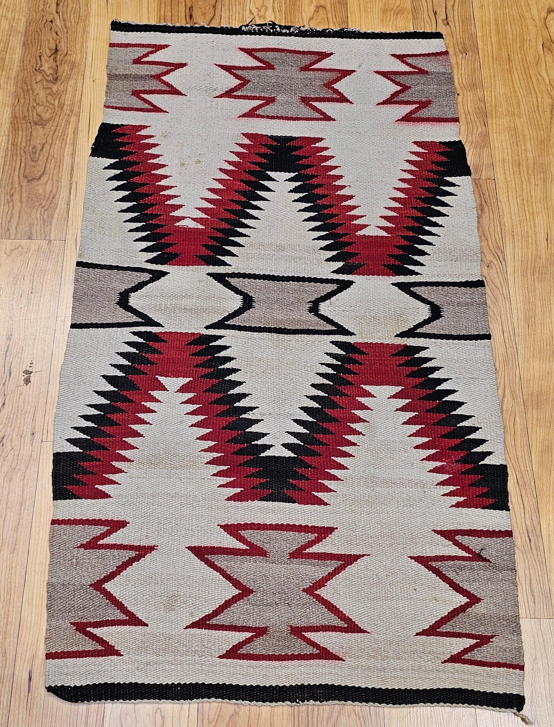 This vintage Native American Navajo rug, woven circa the mid-1900s, is a striking example of the famed “Eye Dazzler” pattern, known for its bold, high-contrast geometry and visual intensity. Set against a soft ivory background, the design comes