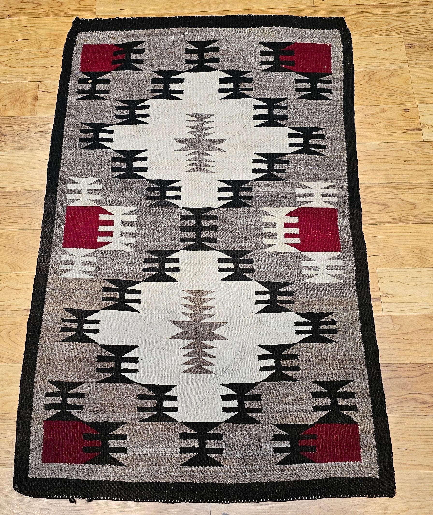 Ein außergewöhnlicher handgewebter Navajo-Teppich aus der Mitte des 20. Jahrhunderts aus dem amerikanischen Südwesten, der ein klassisches geometrisches Design mit zwei kühnen Medaillons auf einem weichen grauen Feld zeigt. Die Komposition ist mit