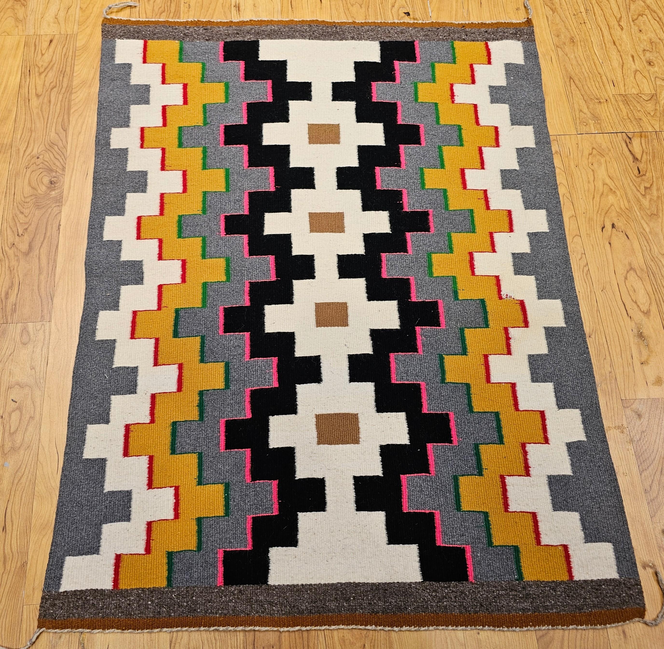 A vibrant and authentic Vintage Native American Navajo rug, this striking textile features a bold geometric tribal pattern rendered in a vivid palette of bright, saturated colors. Woven during the fourth quarter of the 20th century, this piece