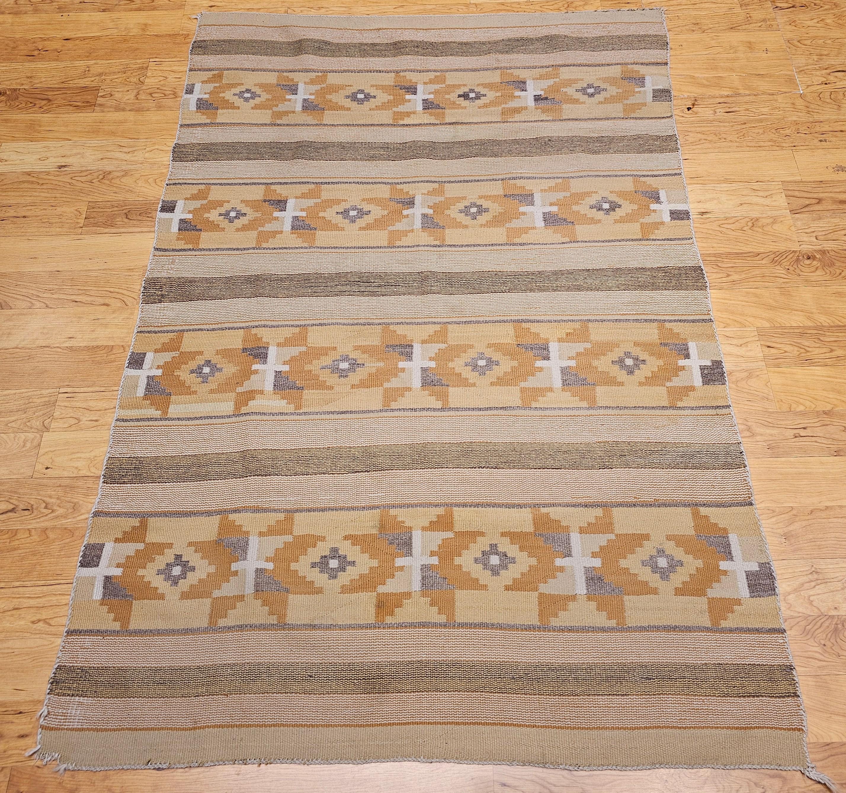 Finely hand-woven Native American Navajo Chinle rug in gold, yellow, ivory, brown, and gray colors from the SW United States from the early 1900s.   The Chinle rug is in the banded stripe pattern with small geometric medallions in each row. The