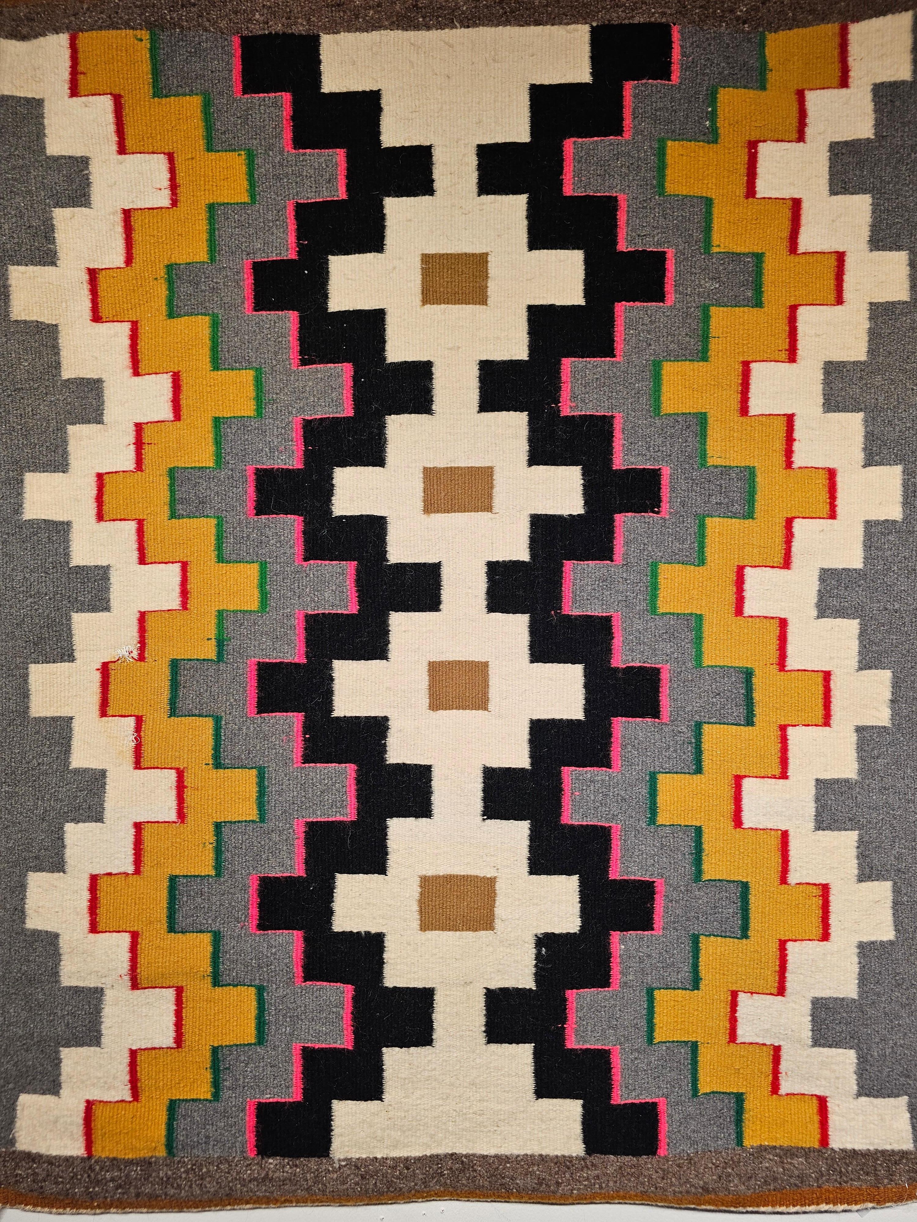 Vintage Native American Navajo rug is in a geometric pattern with bright colors from the 4th quarter of the 1900s. Navajo weavers use mostly natural organic dyes that are available around their tribal land although they also use synthetic dyes that