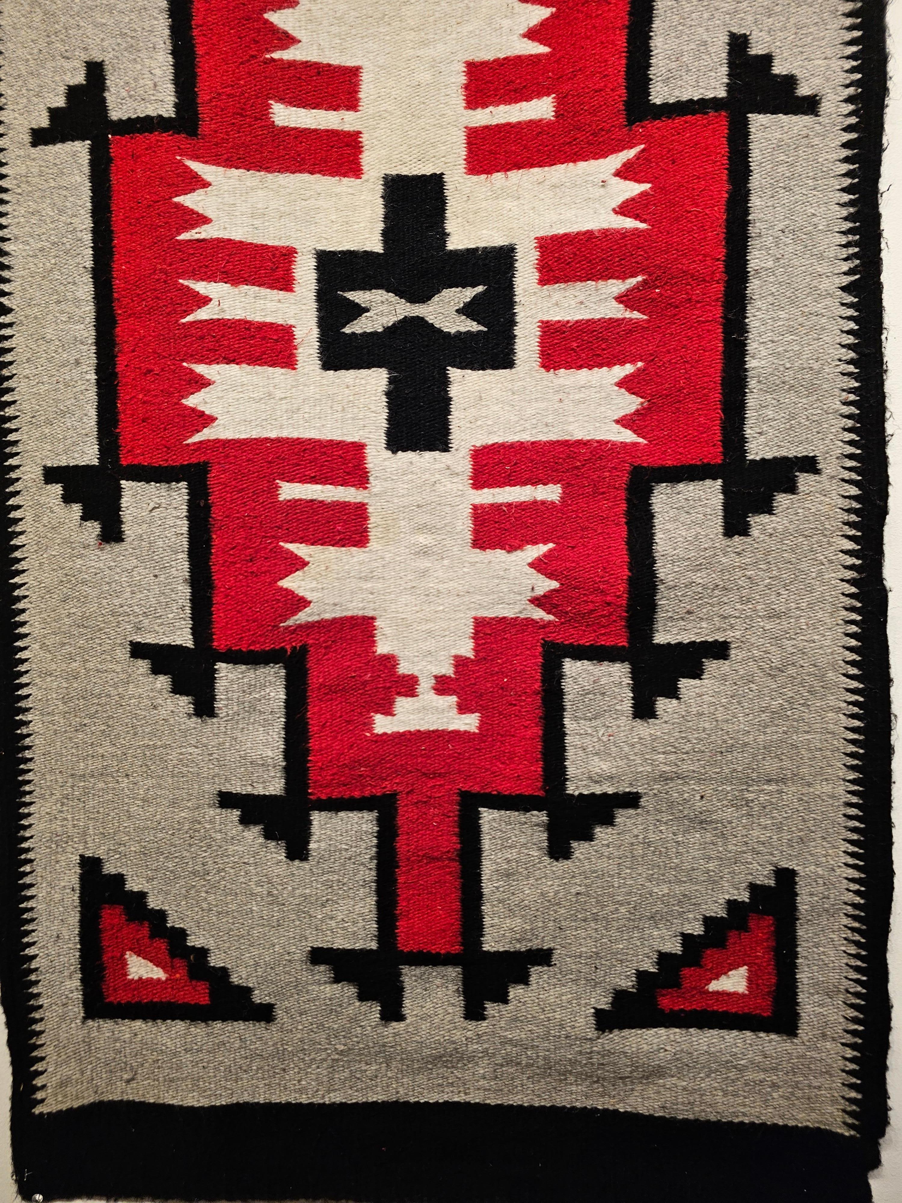 Vintage amerikanischer Navajo-Teppich aus der Mitte der 1900er Jahre. Dieser Navajo-Teppich hat ein Medaillon-Muster in Rot und Weiß mit einer schwarzen Bordüre, die den größten Teil des Feldes bedeckt, das in Grau gehalten ist. Die Navajo-Weber