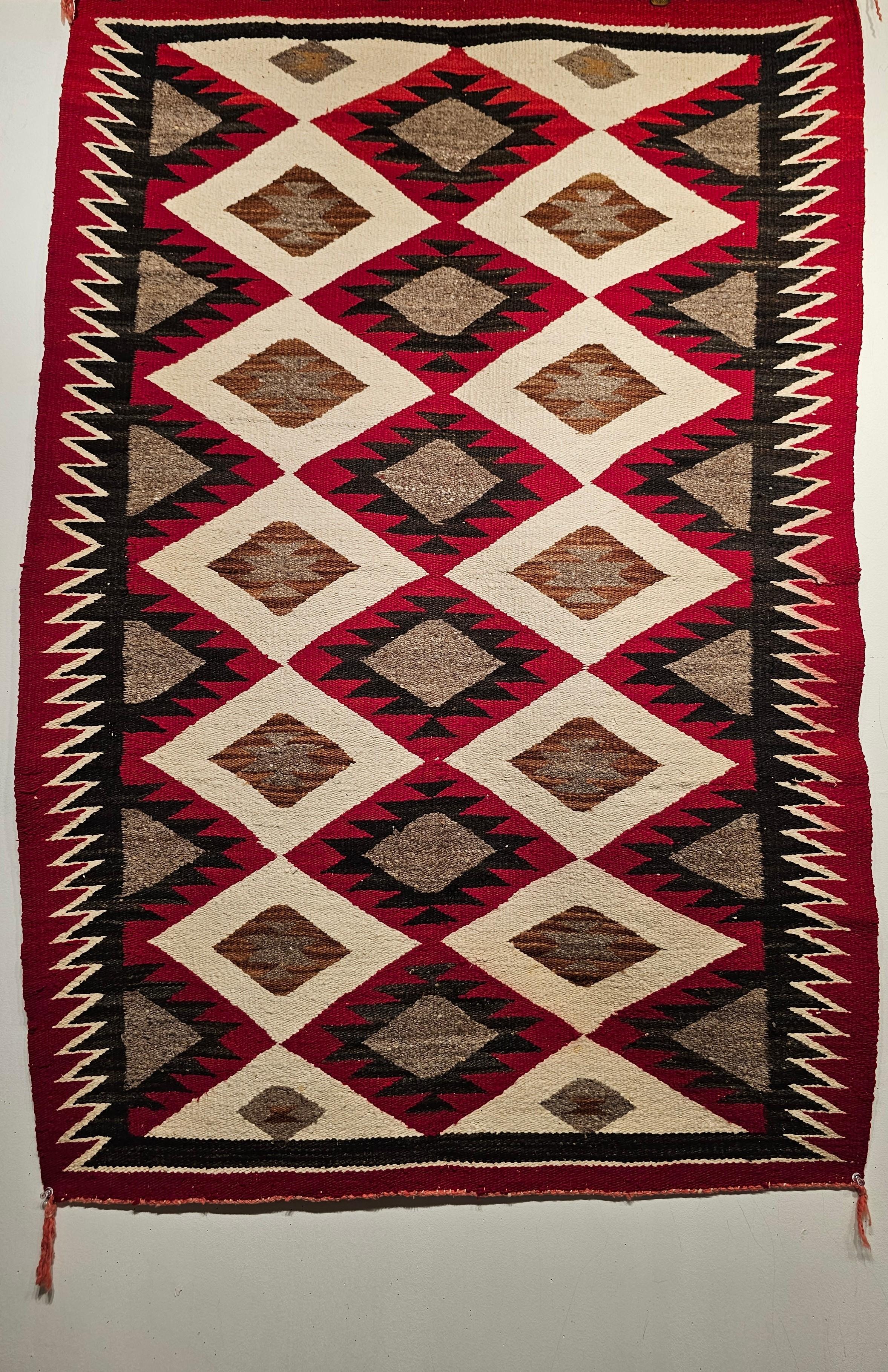 Native American Navajo Rug in Eye Dazzler Pattern in ivory, burgundy, brown, gray and black colors from the SW United States from the early 1900s.  This Navajo rug is in a geometric design consisting of three rows of different size diamond forms in