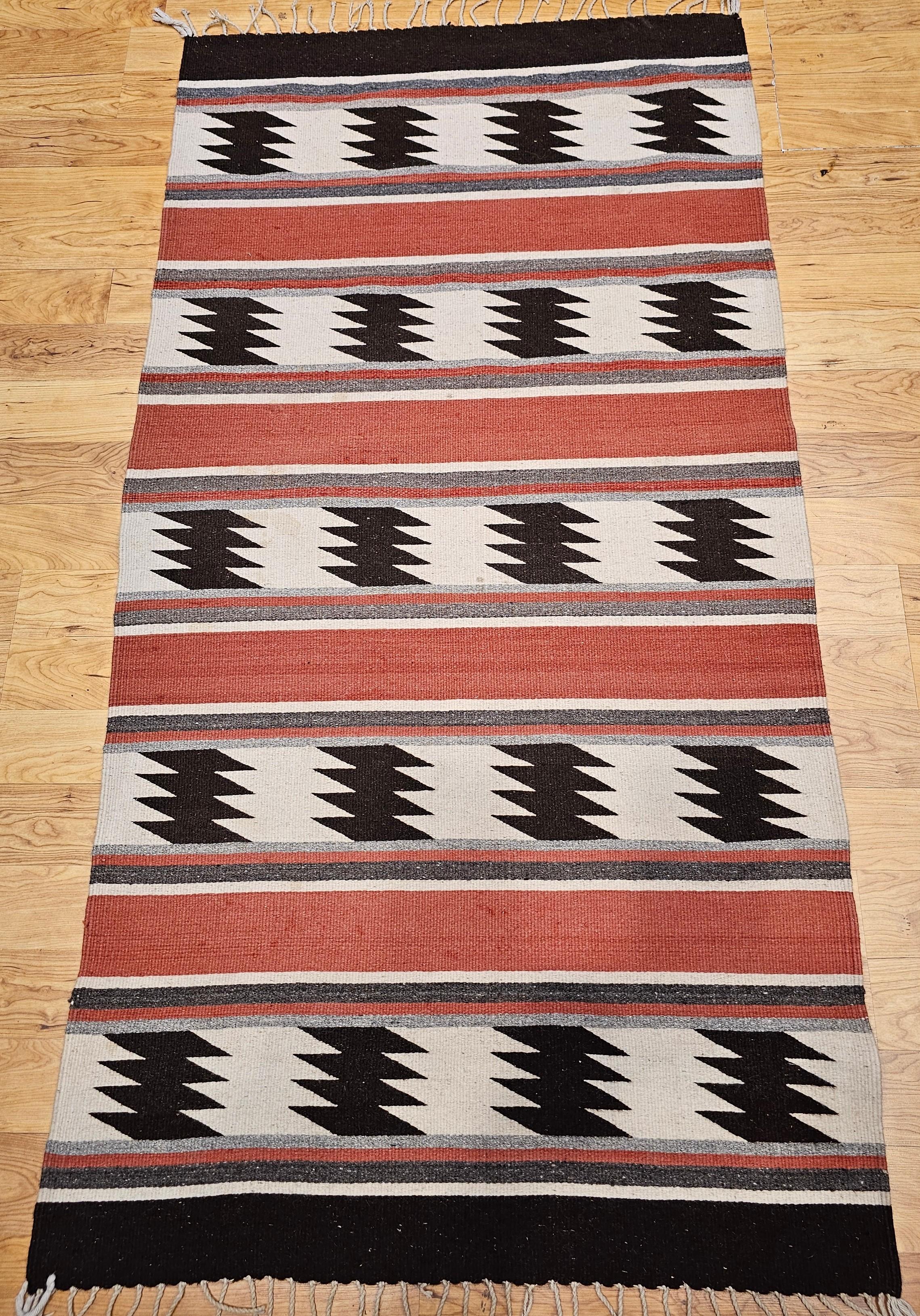 Add timeless style and cultural depth to your space with this vintage Native American Navajo area rug, handwoven in the Southwestern United States and featuring a warm, earthy color palette of brick red, brown, black, ivory, and gray. Crafted during