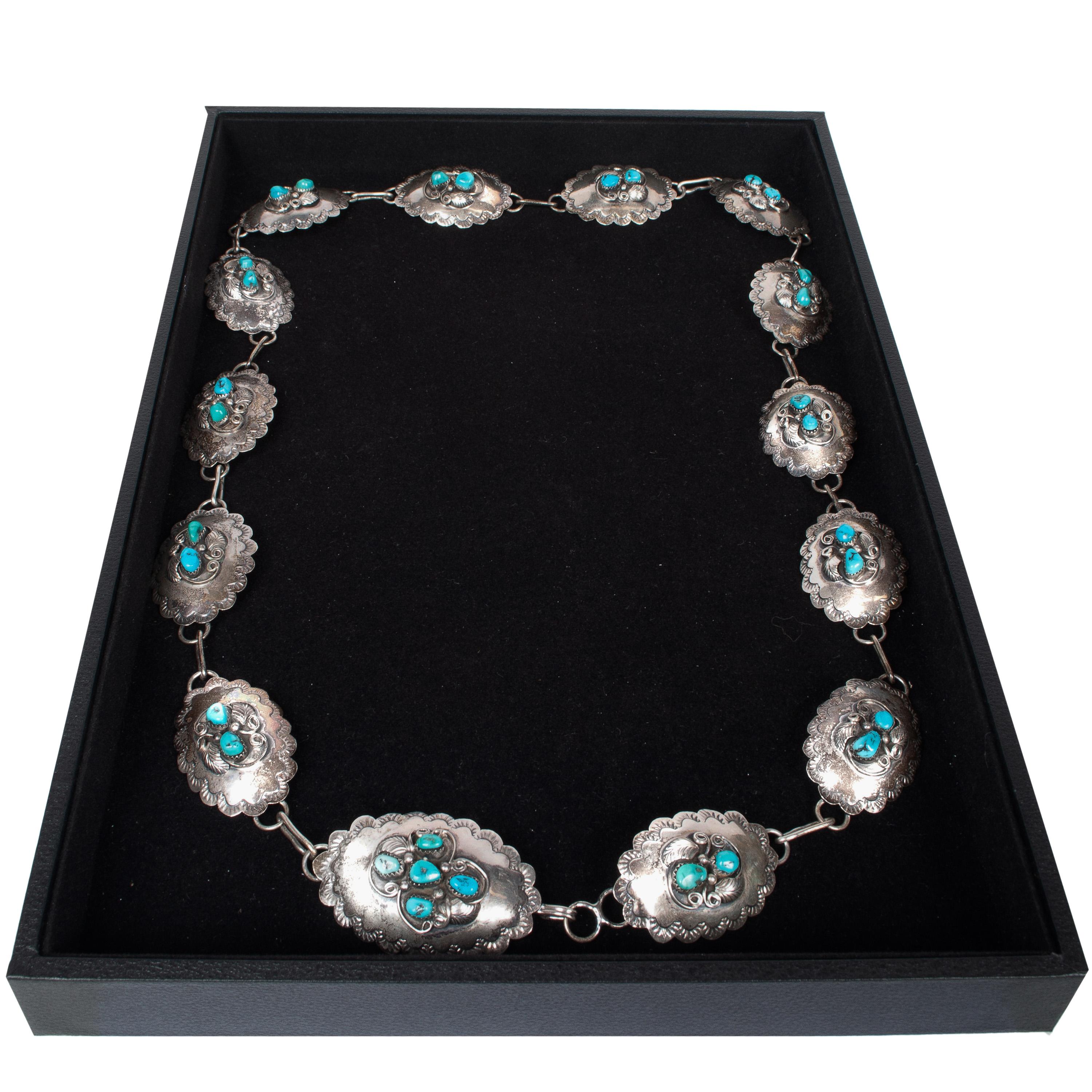 Un'ottima cintura vintage in argento sterling e turchese blu dei nativi americani Navajo Concho, circa 1950.
Questa cintura Navajo molto attraente è composta da dischi ovali d'argento con contorni floreali lavorati e pressati, ogni disco ovale è