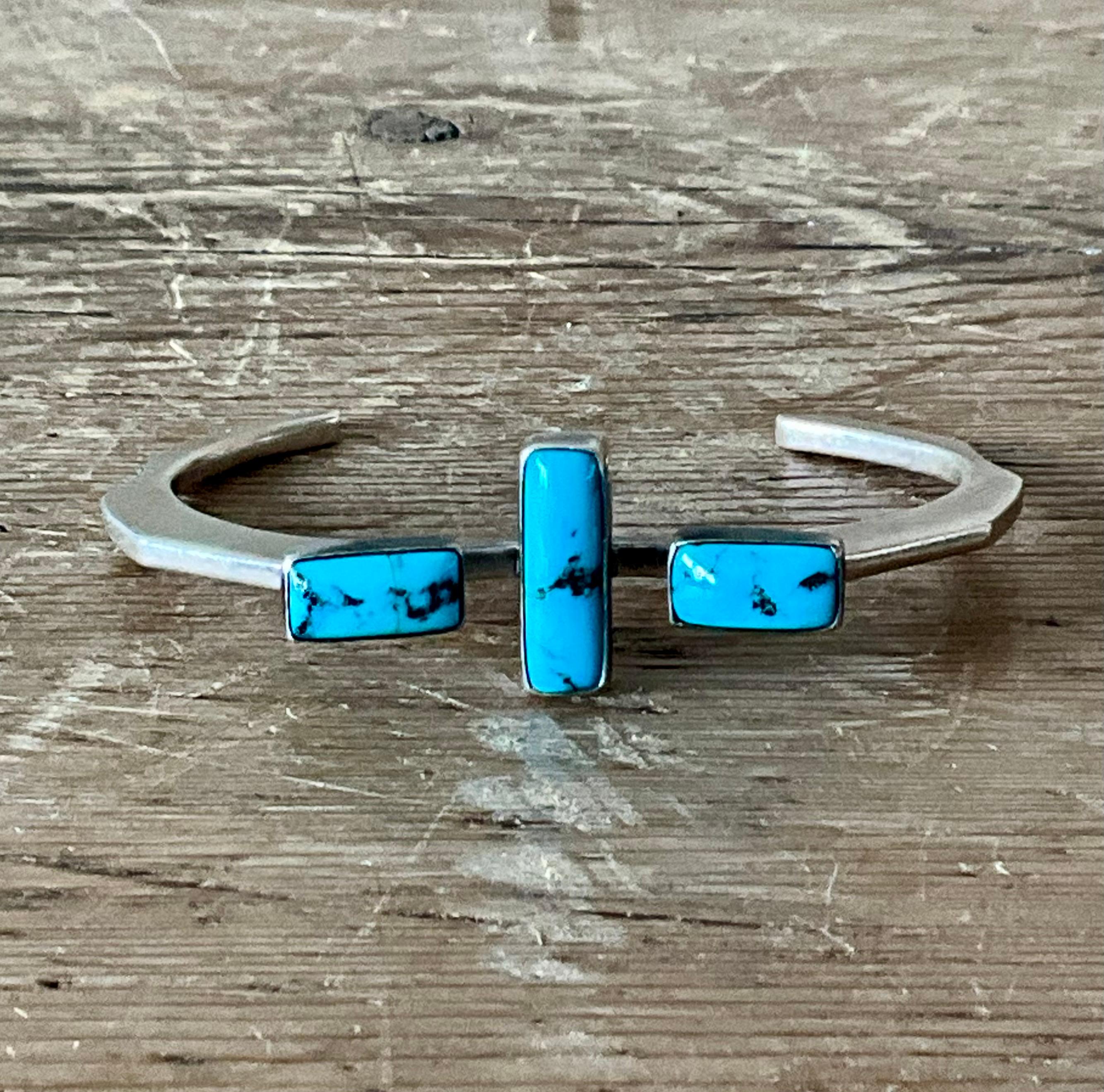 Questo bracciale vintage in argento Navajo dei Nativi Americani mostra un'eccezionale maestria e uno stile sud-occidentale senza tempo. Realizzato a mano da un artigiano Navajo, il bracciale presenta diverse pietre di turchese naturale, ognuna con