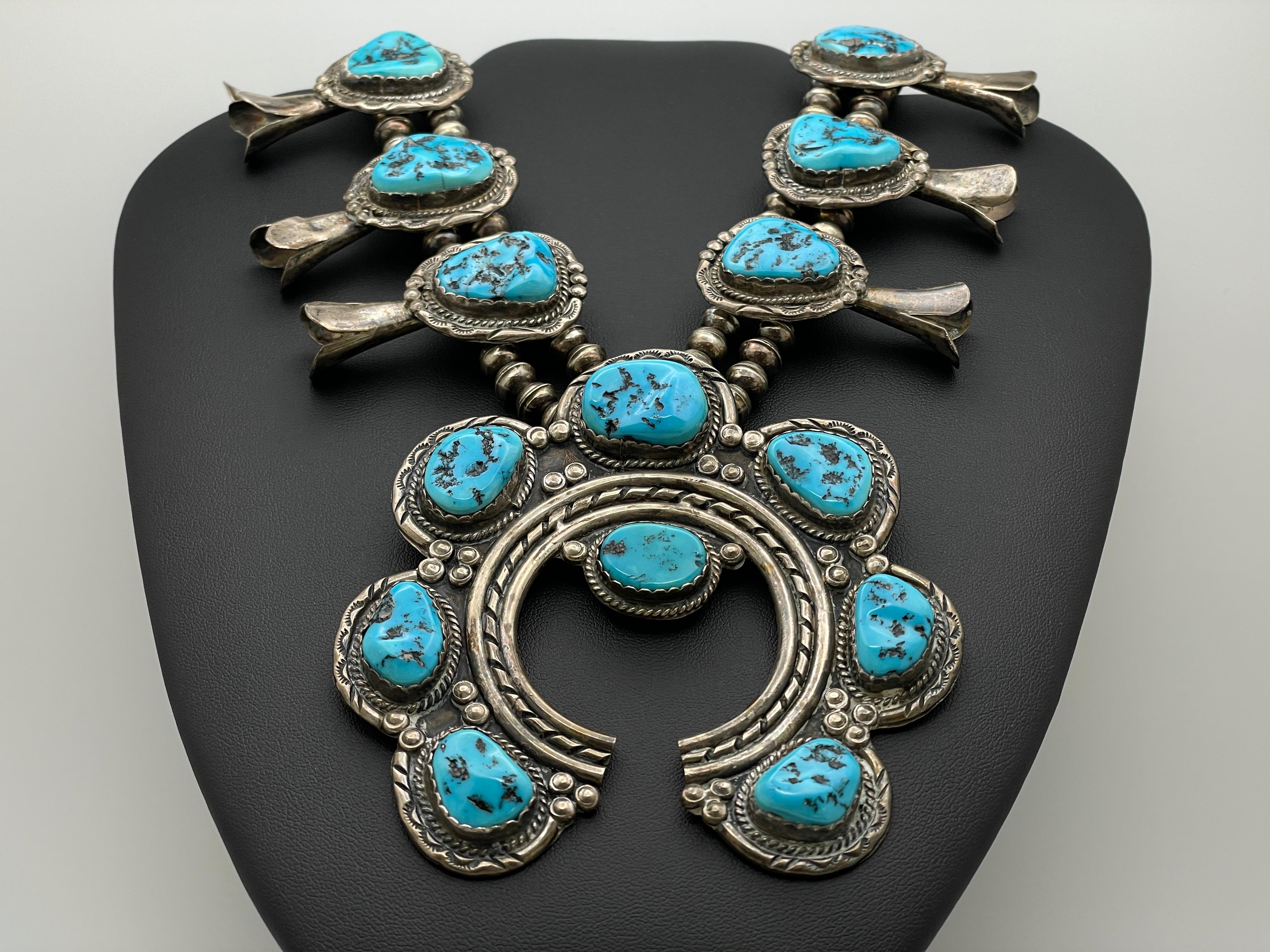 An authentic large vintage Navajo Native American turquoise silver squash blossom necklace. This magnificent features a total of 18 natural blue turquoise cabochons, eight of them set on the intricately patterned and uniquely designed silver naja