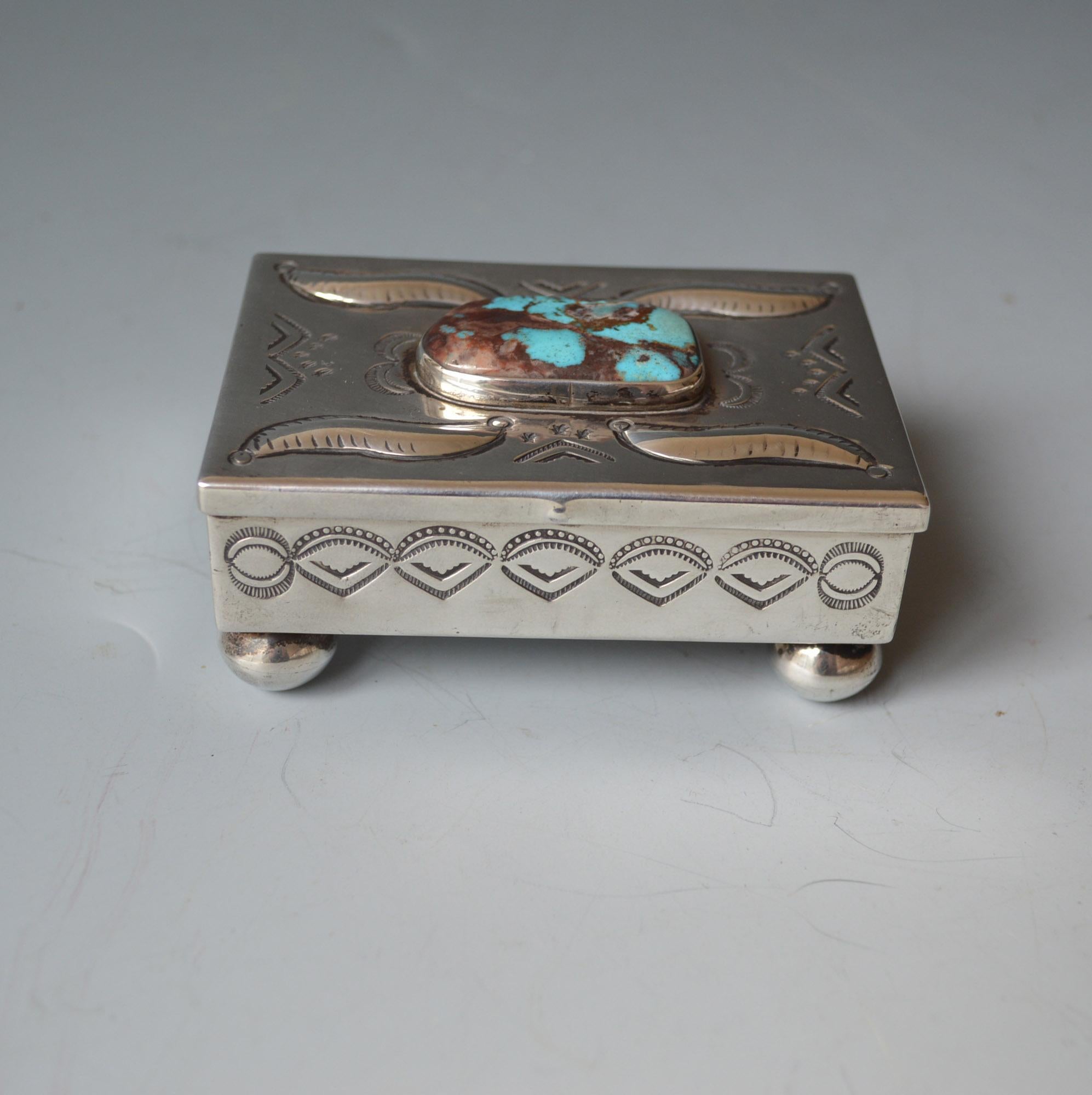 A fine vintage handcrafted Navajo sterling silver box.
A particularly attractive box with Conch stamped and repousse design on the top and sides having a large turquoise cabochon and round ball feet.
Measures: 3 1/2 x 2 3/34 inches. 9 x 6 cm.
