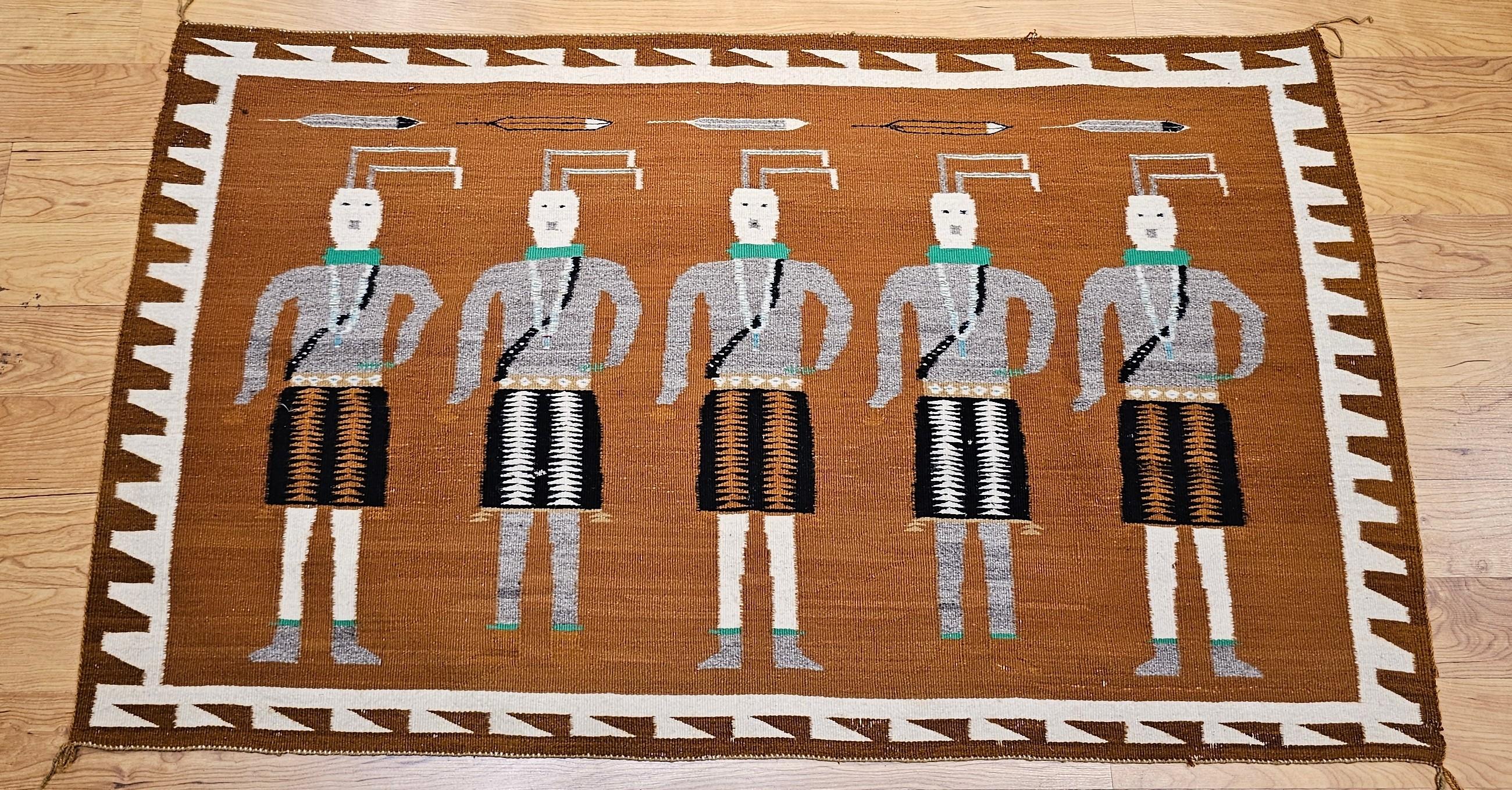 This vintage Native American Navajo Yei rug, woven in the mid-1900s, features a powerful and visually captivating design with five Yei deity figures standing side-by-side. Set against a rich brown background, the Yei figures are woven in ivory,