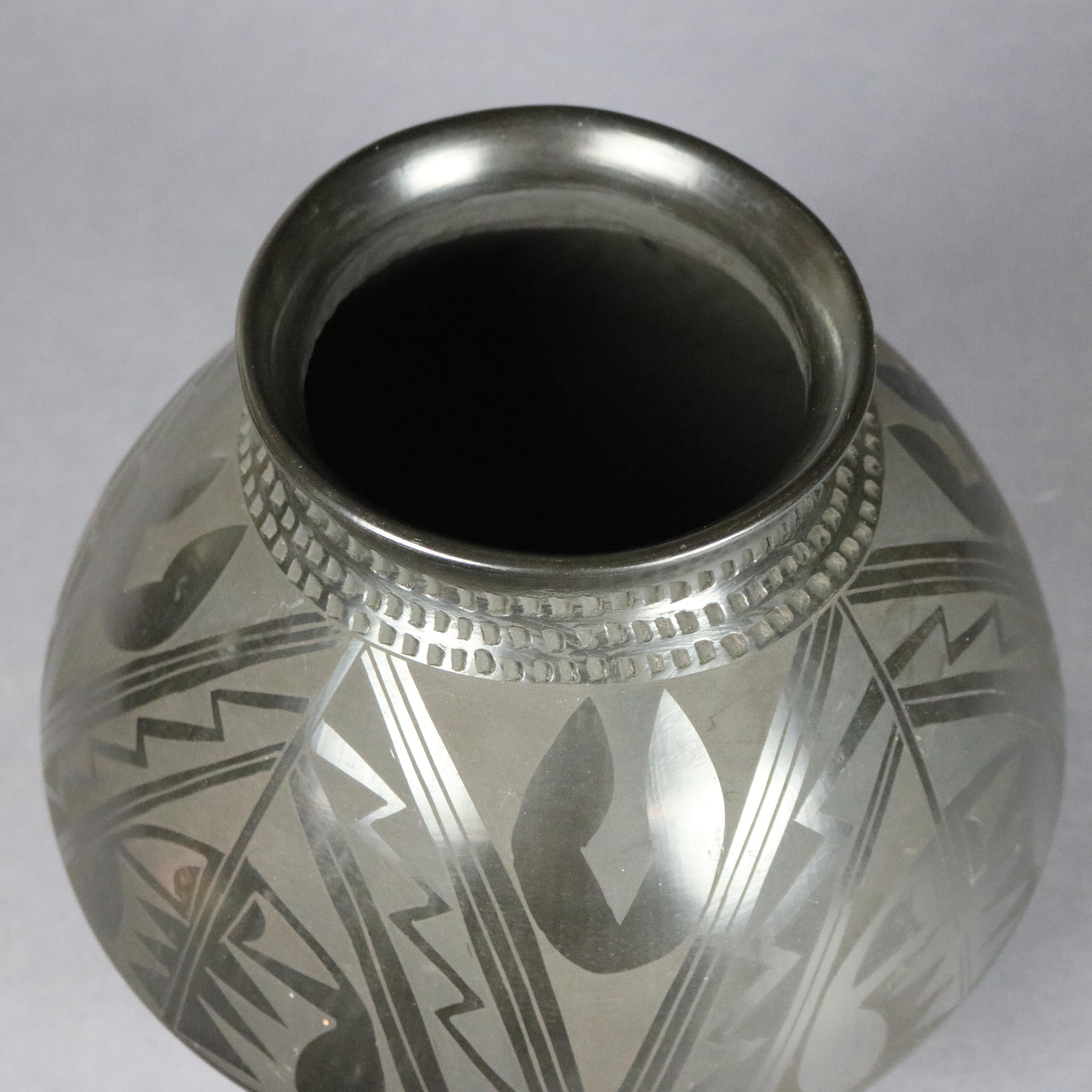 A vintage Native American San Ildefonso olla jar offers blackware pottery construction with engraved geometric design and artist signed on base Julio Silvera, circa 1930

Measures: 8.75