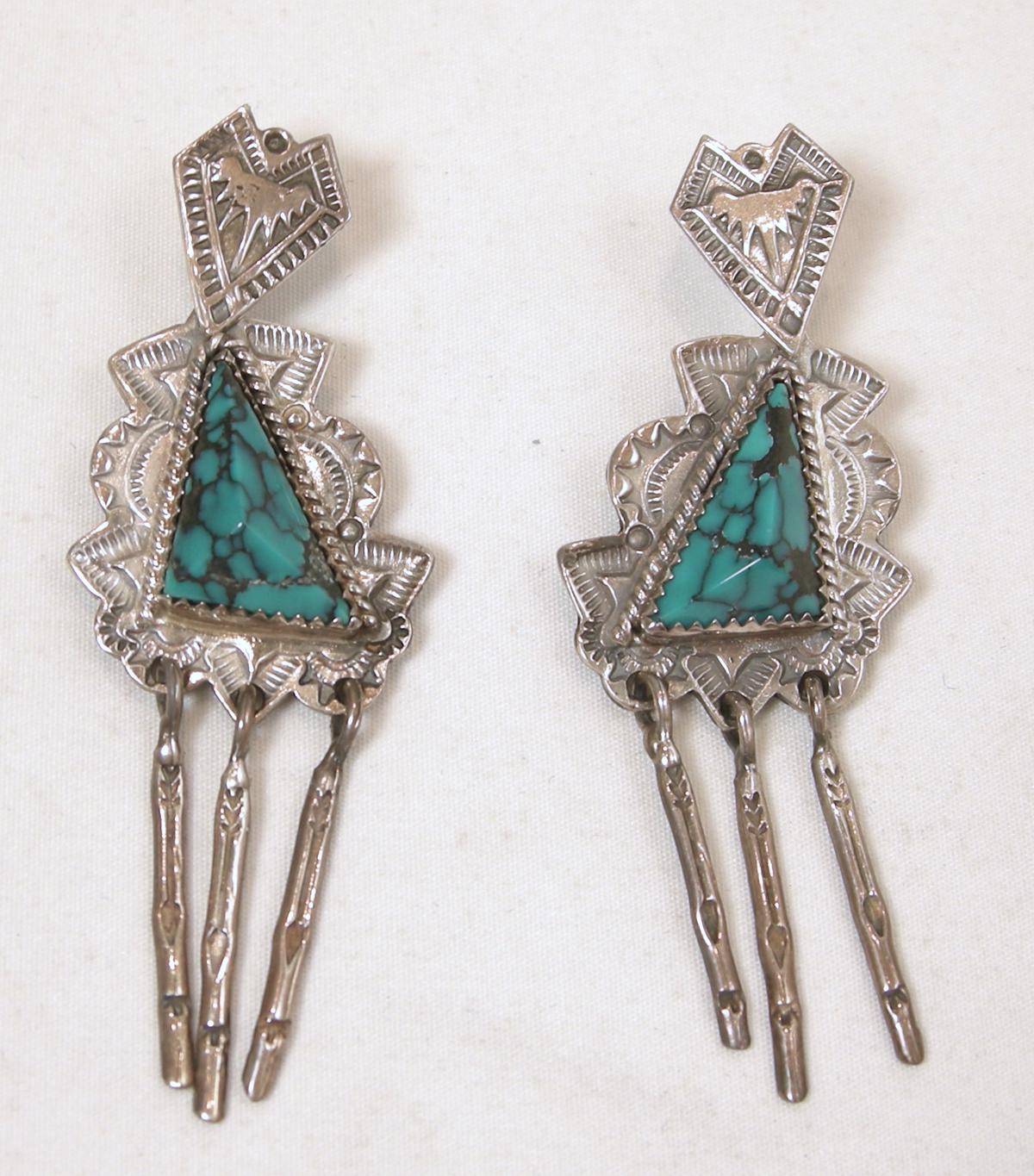 This vintage Native American signed JR Silversmiths earrings have triangular turquoise stones surrounding by a sterling setting.  Three rows of sterling hang down.  These pierced earrings measure 2-5/8” x 1” and are signed “JR Silversmiths”.  They